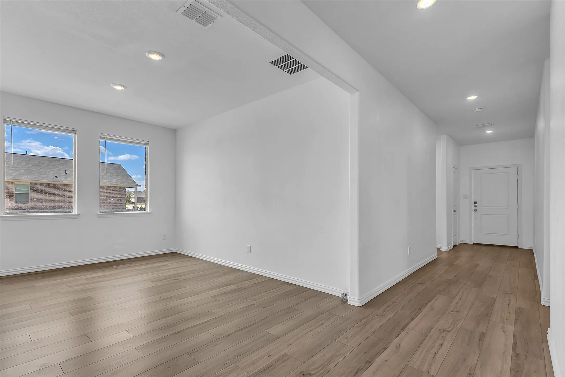 Dining room with two windows and recessed lights, open to the front hallway leading back to the entry door