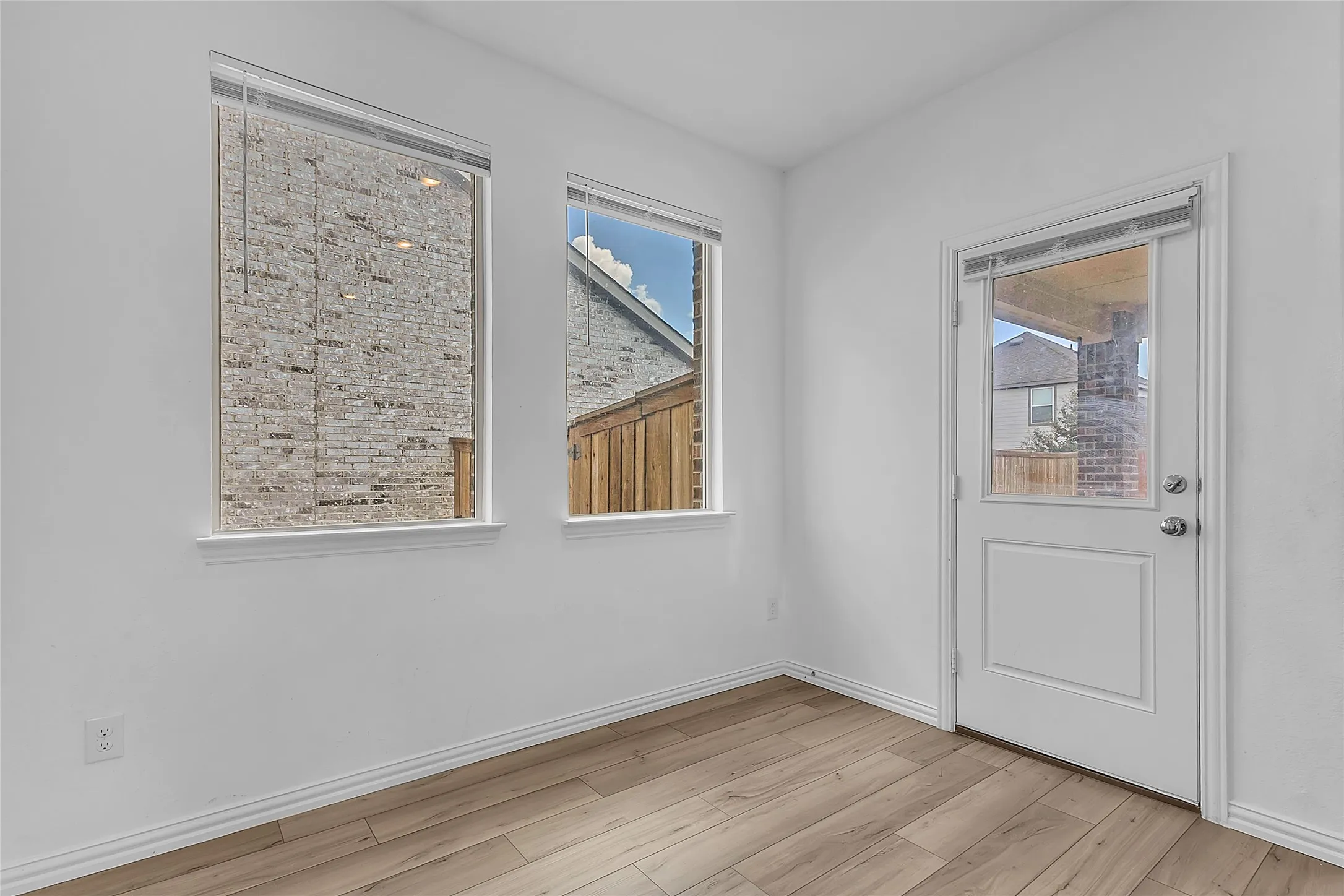 Breakfast nook with two windows and a half-glass door leading out to the covered back patio