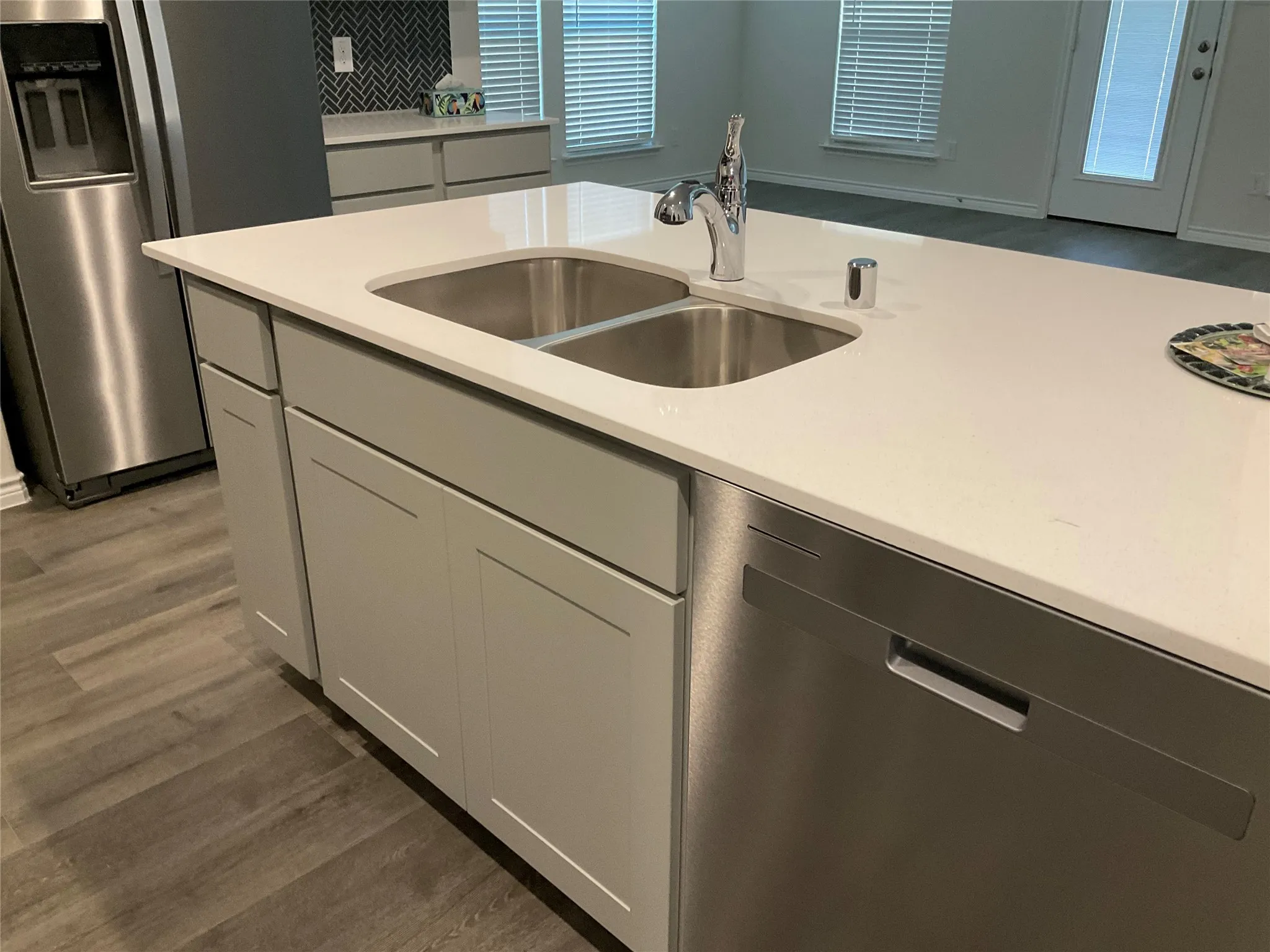 Kitchen featuring wood finished floors, a sink, decorative backsplash, light countertops, and stainless steel appliances