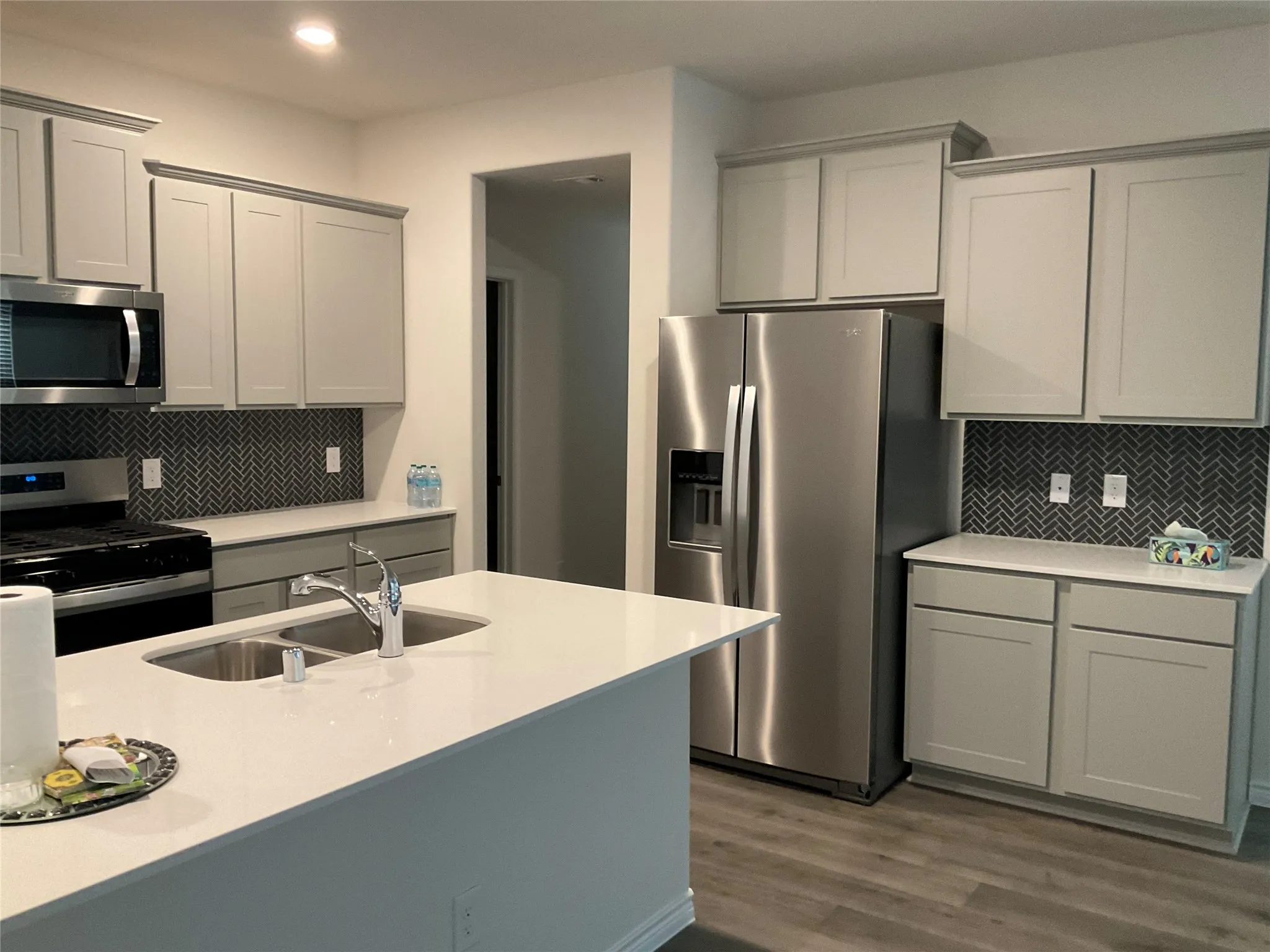 Kitchen with a sink, wood finished floors, gray cabinets, and stainless steel appliances