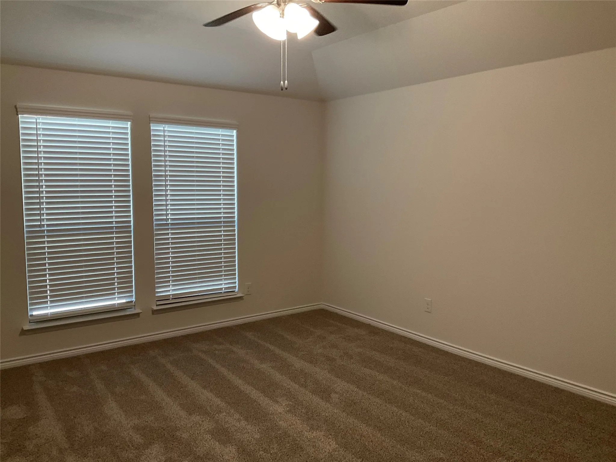 Spare room with ceiling fan, baseboards, lofted ceiling, and carpet floors