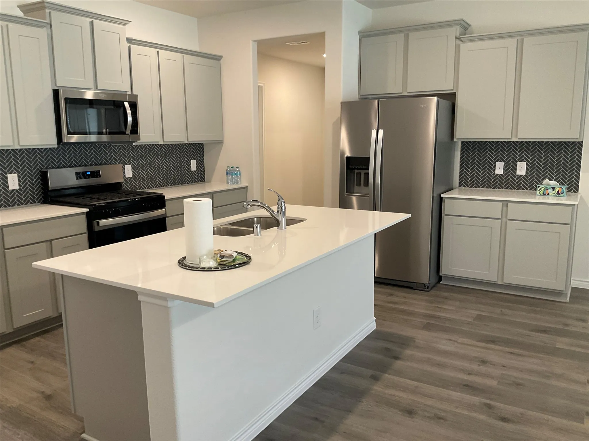 Kitchen with dark wood finished floors, light countertops, gray cabinets, appliances with stainless steel finishes, and a sink