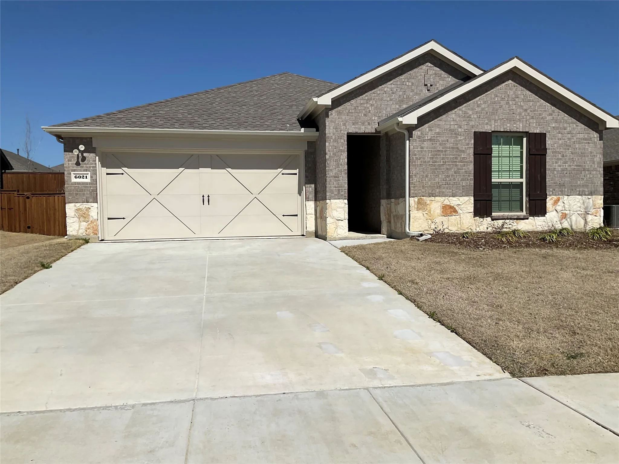 Single story home featuring a garage, brick siding, stone siding, and driveway