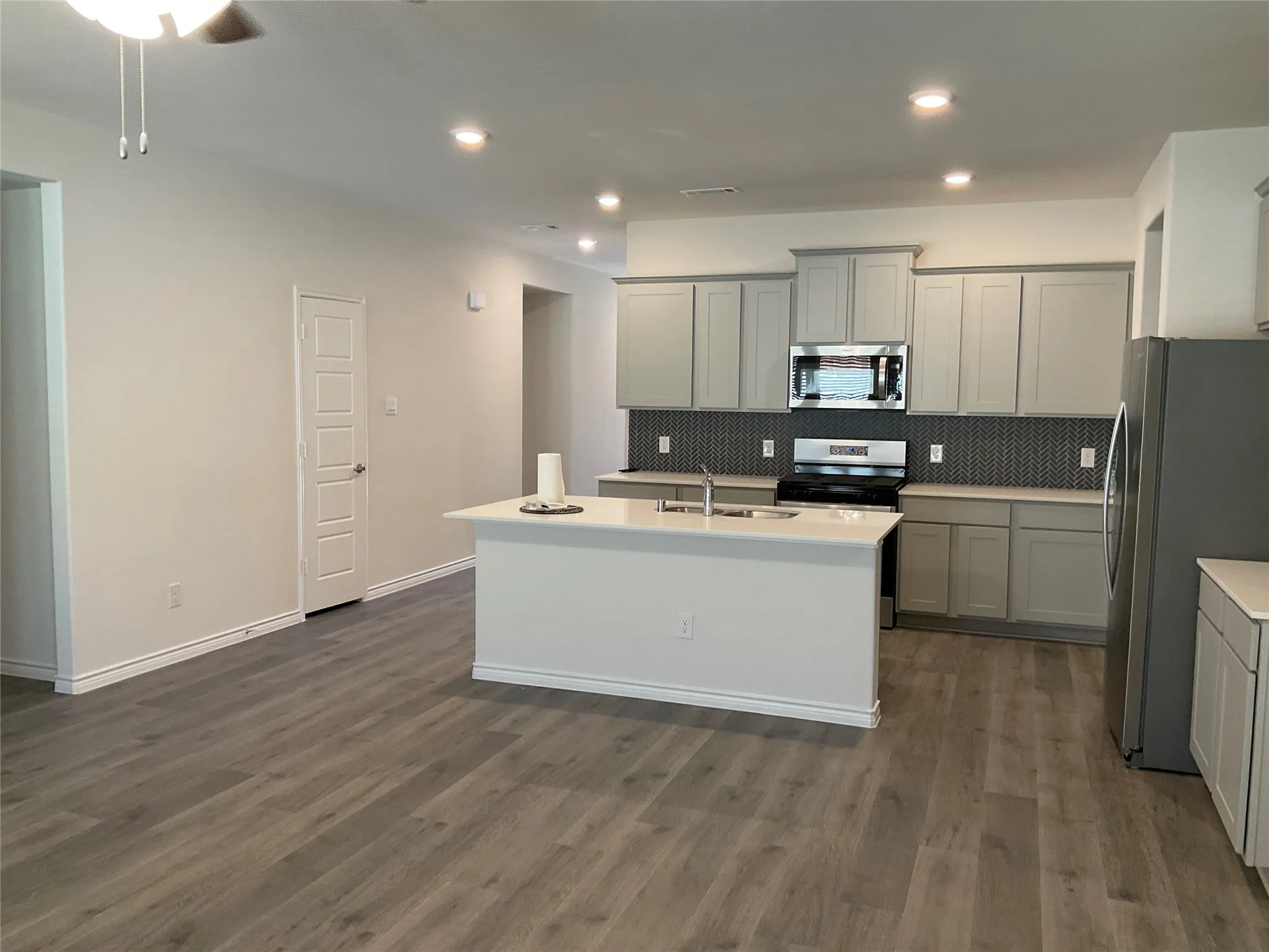 Kitchen with a sink, gray cabinetry, a kitchen island with sink, and stainless steel appliances