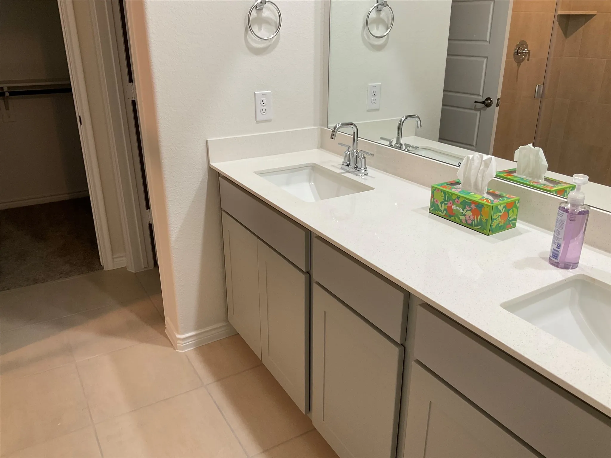 Full bathroom featuring tile patterned flooring, double vanity, tiled shower, and a sink