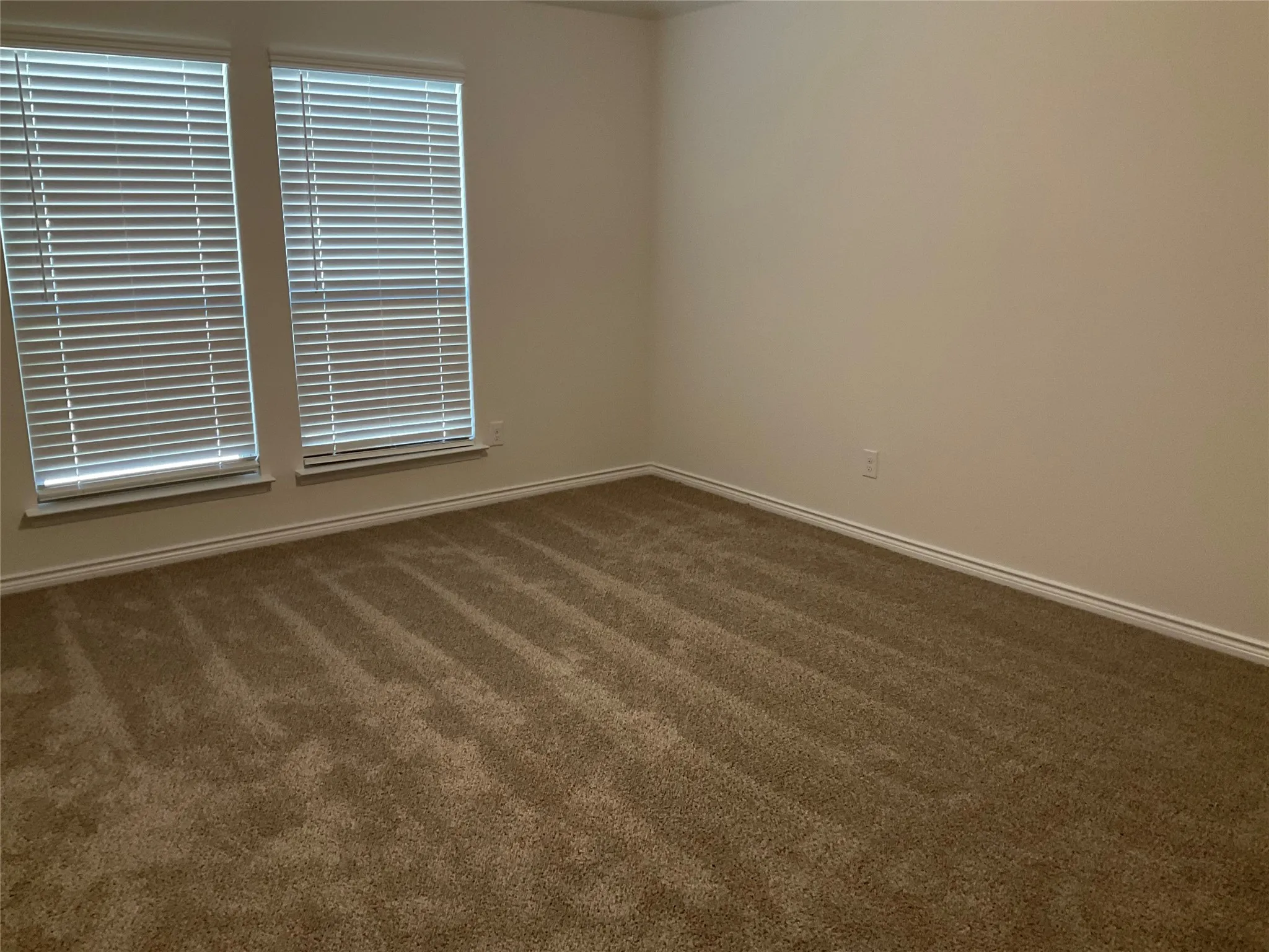 Empty room featuring baseboards and dark colored carpet