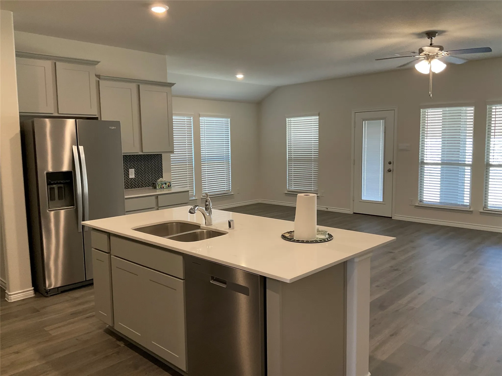 Kitchen featuring a kitchen island with sink, a sink, light countertops, appliances with stainless steel finishes, and open floor plan