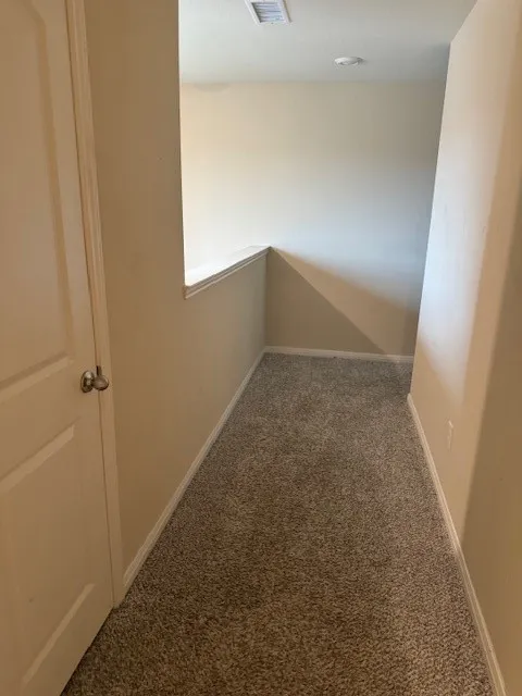 Neutral tone wall paint, textured carpeting, recessed ceiling lighting, and a white door with a round knob