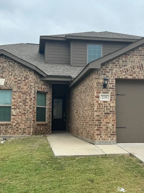 Brick facade with coordinating siding accents, an attached garage, and a covered entry
