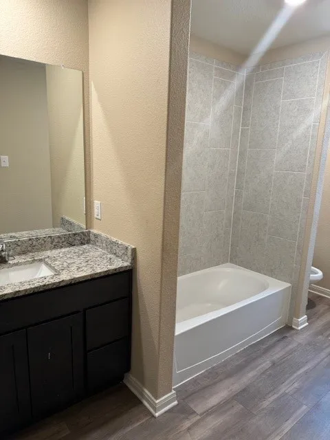 Bathroom featuring a built-in vanity with a granite countertop, undermount sink, and dark wood-finish cabinetry