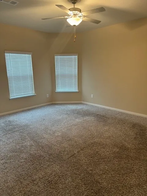 Carpeted flooring with multiple windows featuring blinds and a ceiling fan with integrated lighting
