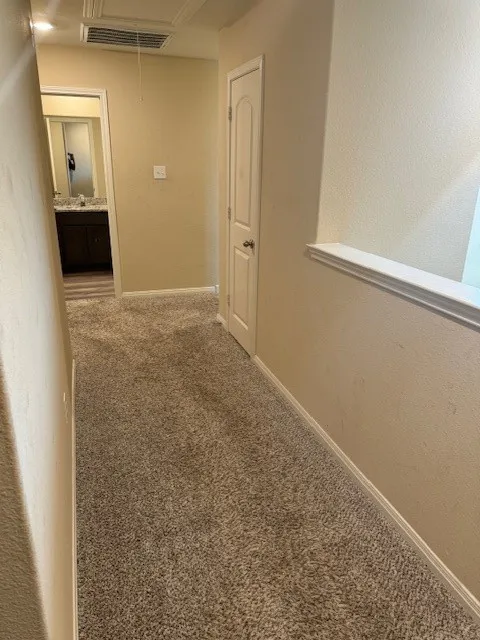 Textured carpeting throughout, featuring a built-in linen closet, and a half-wall architectural element
