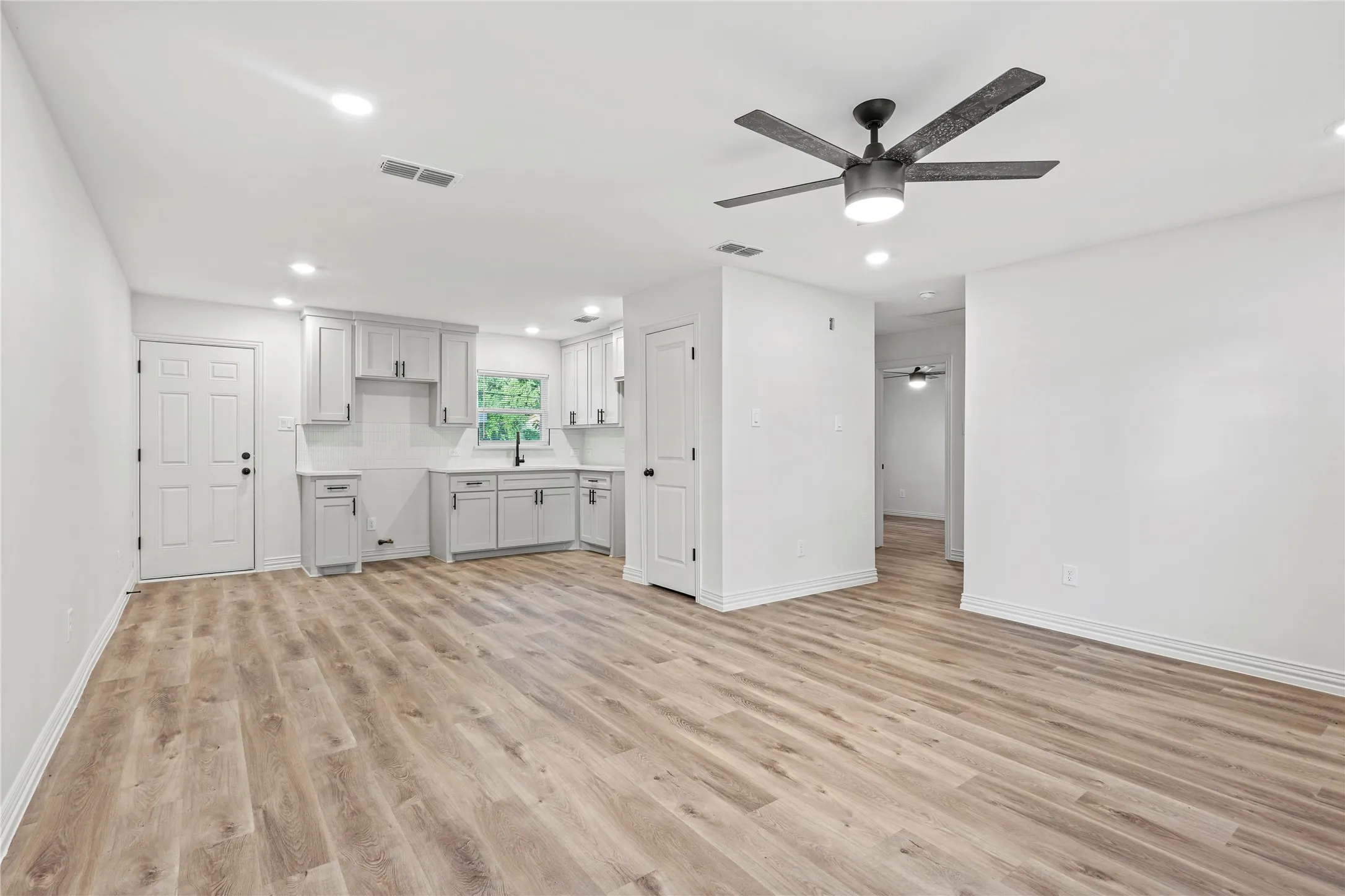 Unfurnished living room with ceiling fan, light wood-style floors, baseboards, and recessed lighting
