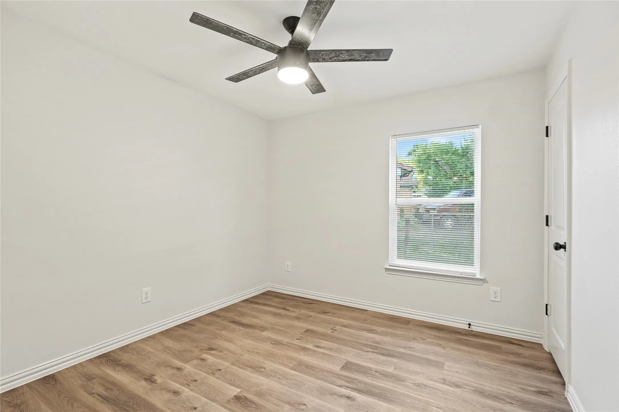 Unfurnished room with light wood finished floors, a ceiling fan, and baseboards