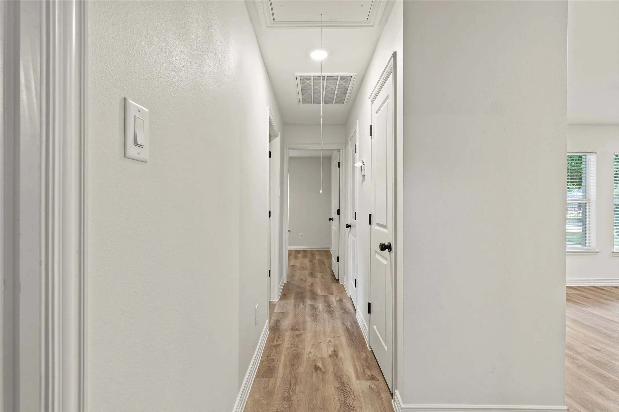 Hall featuring attic access, light wood-type flooring, and baseboards