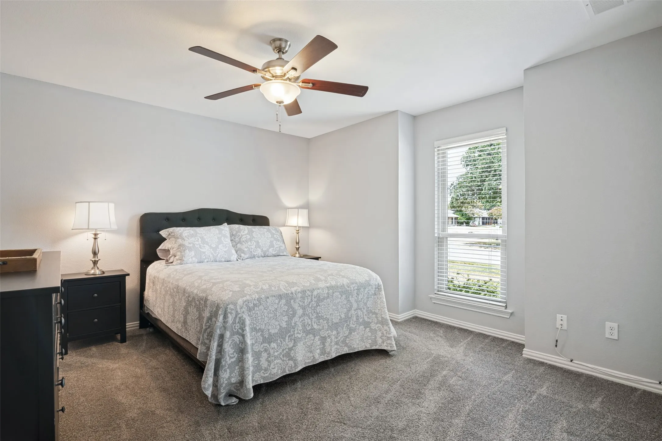 Neutral wall paint, ceiling fan with light fixture, window with blinds, and carpet flooring
