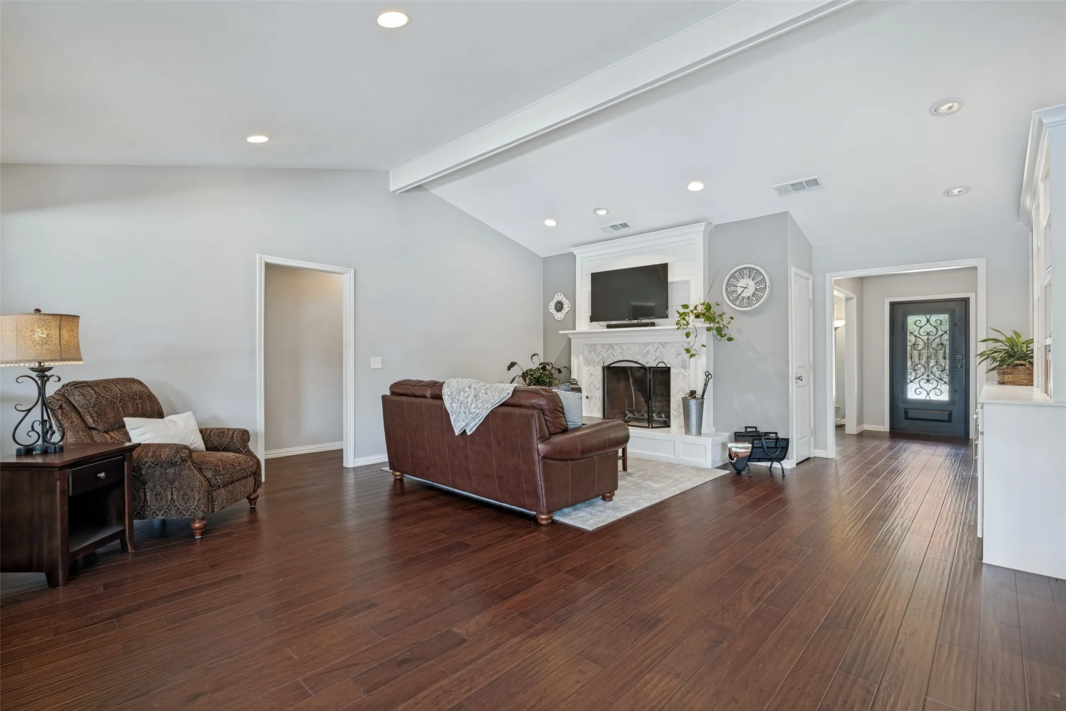 Vaulted ceiling with recessed lighting, wood-finish flooring, fireplace with a decorative mantel, and an ornate front entry door