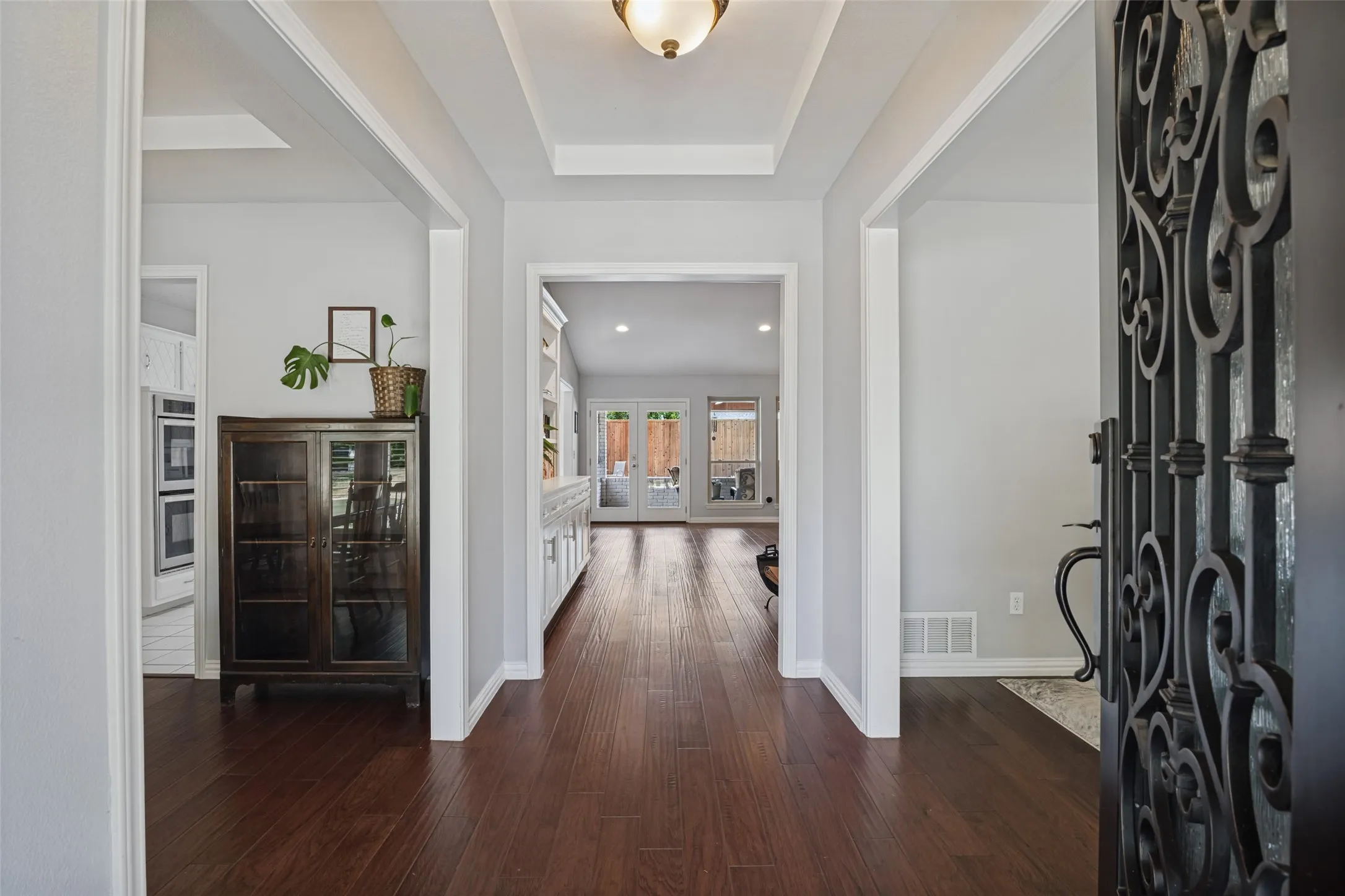 Entryway with dark wood-finish flooring, white trim, and a tray ceiling