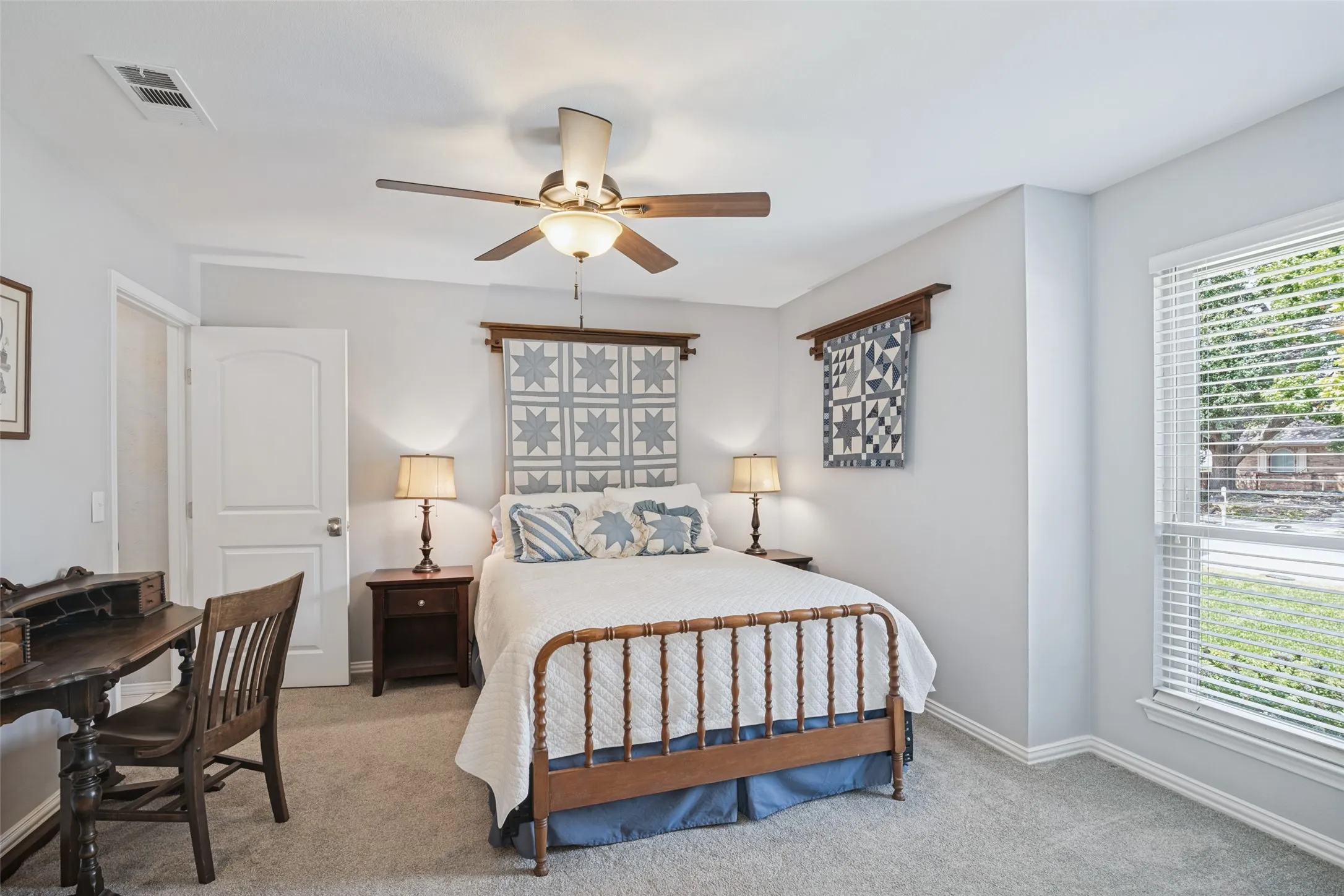 Carpeted room featuring a ceiling fan with integrated lighting, a white paneled door, and a window with blinds