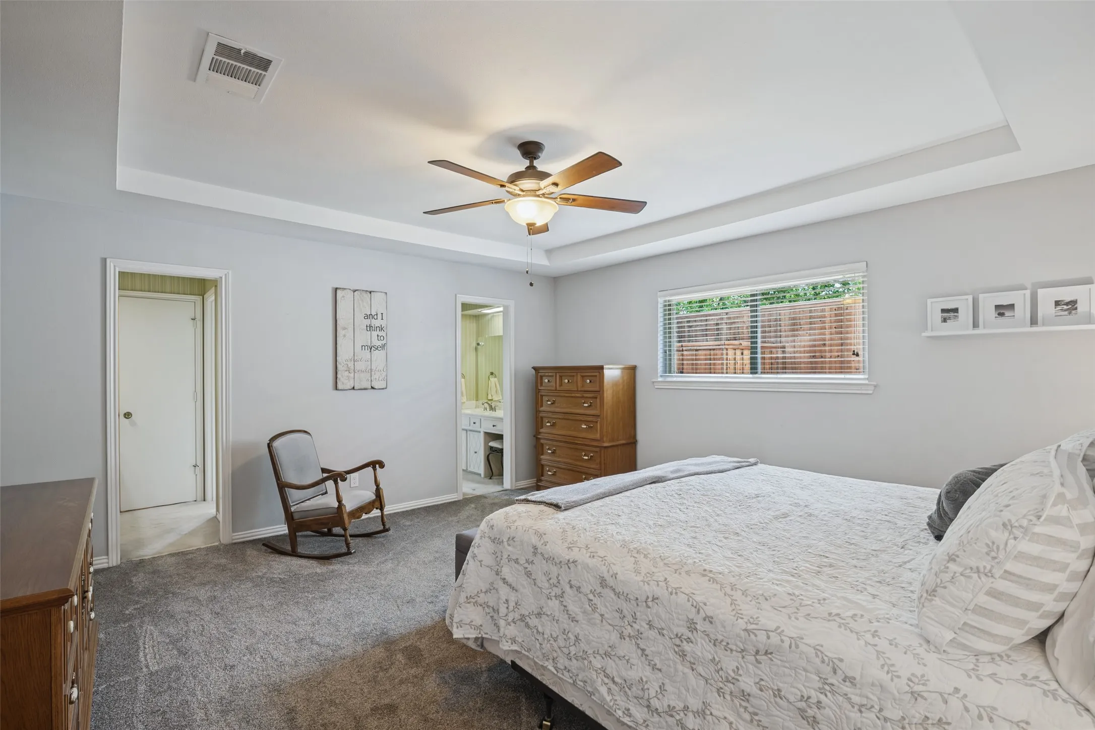 Tray ceiling with a ceiling fan, light gray wall paint, window with blinds, and gray carpet flooring