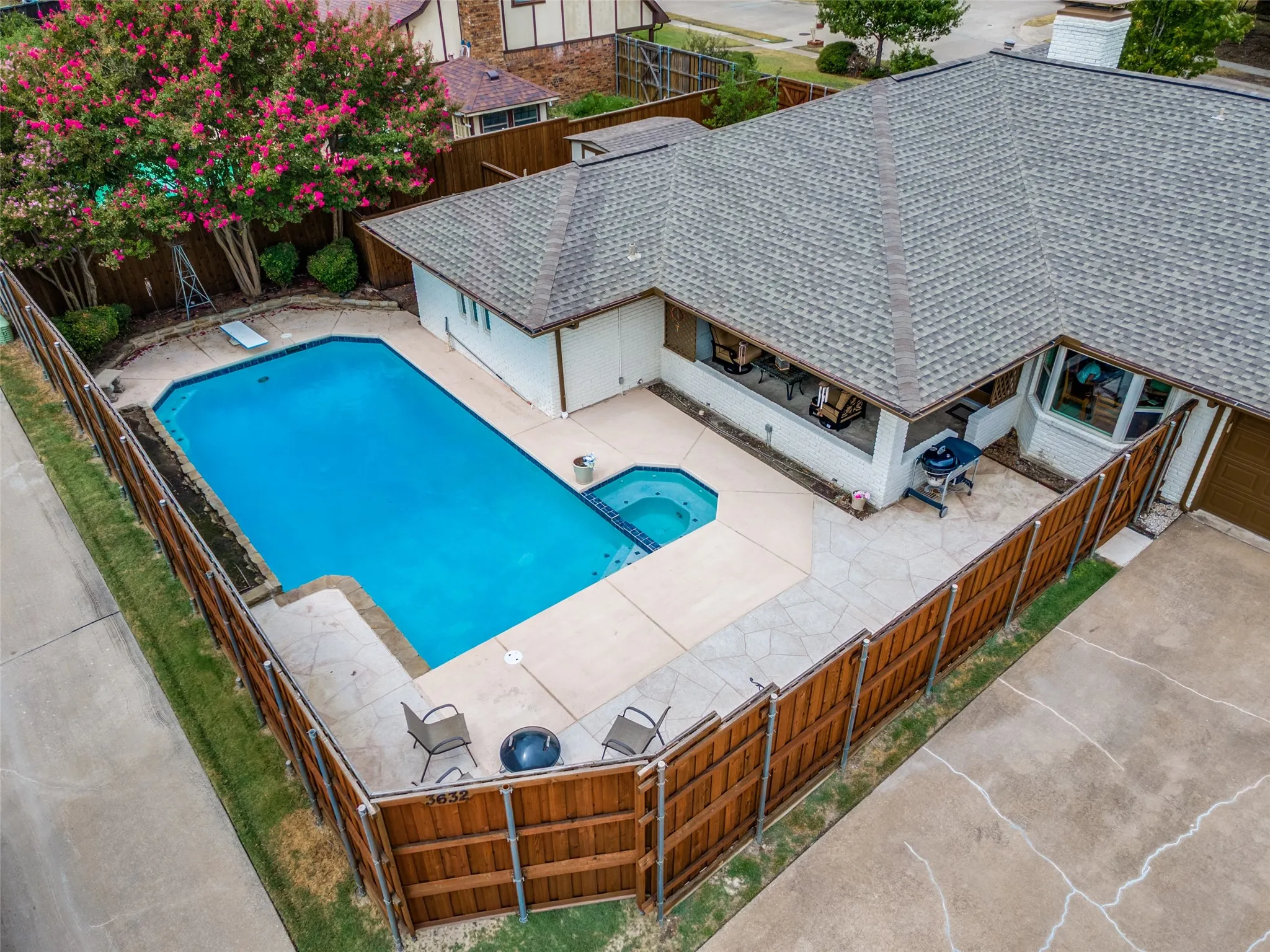 Private backyard featuring a rectangular pool with an attached spa, wood privacy fencing, and stone paver patio