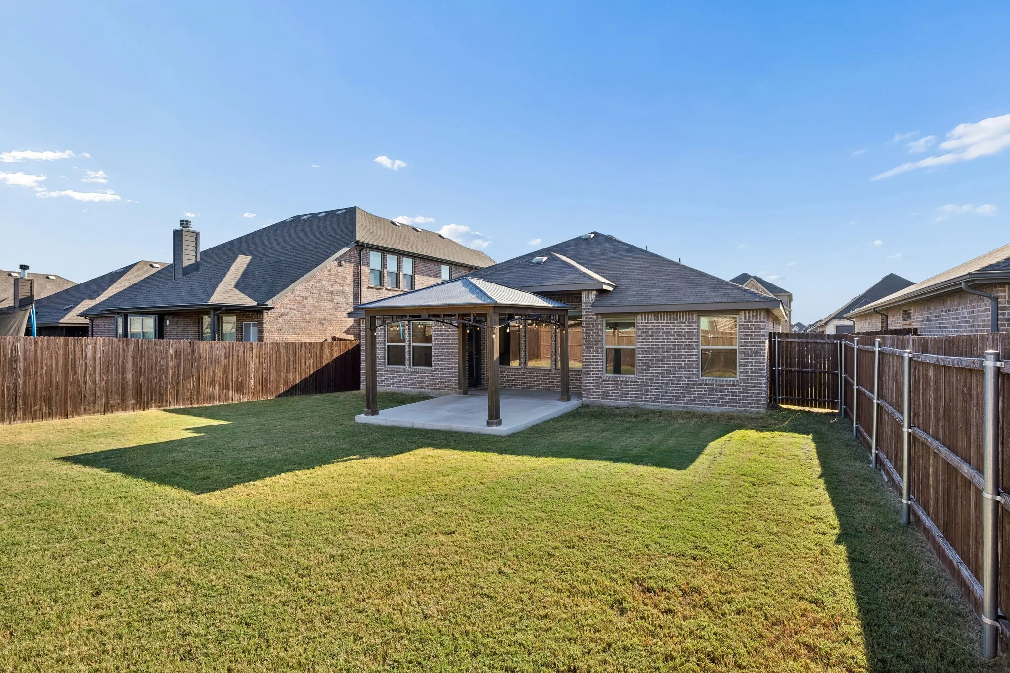 Great backyard with an extended concrete slab with a gazeebo cover