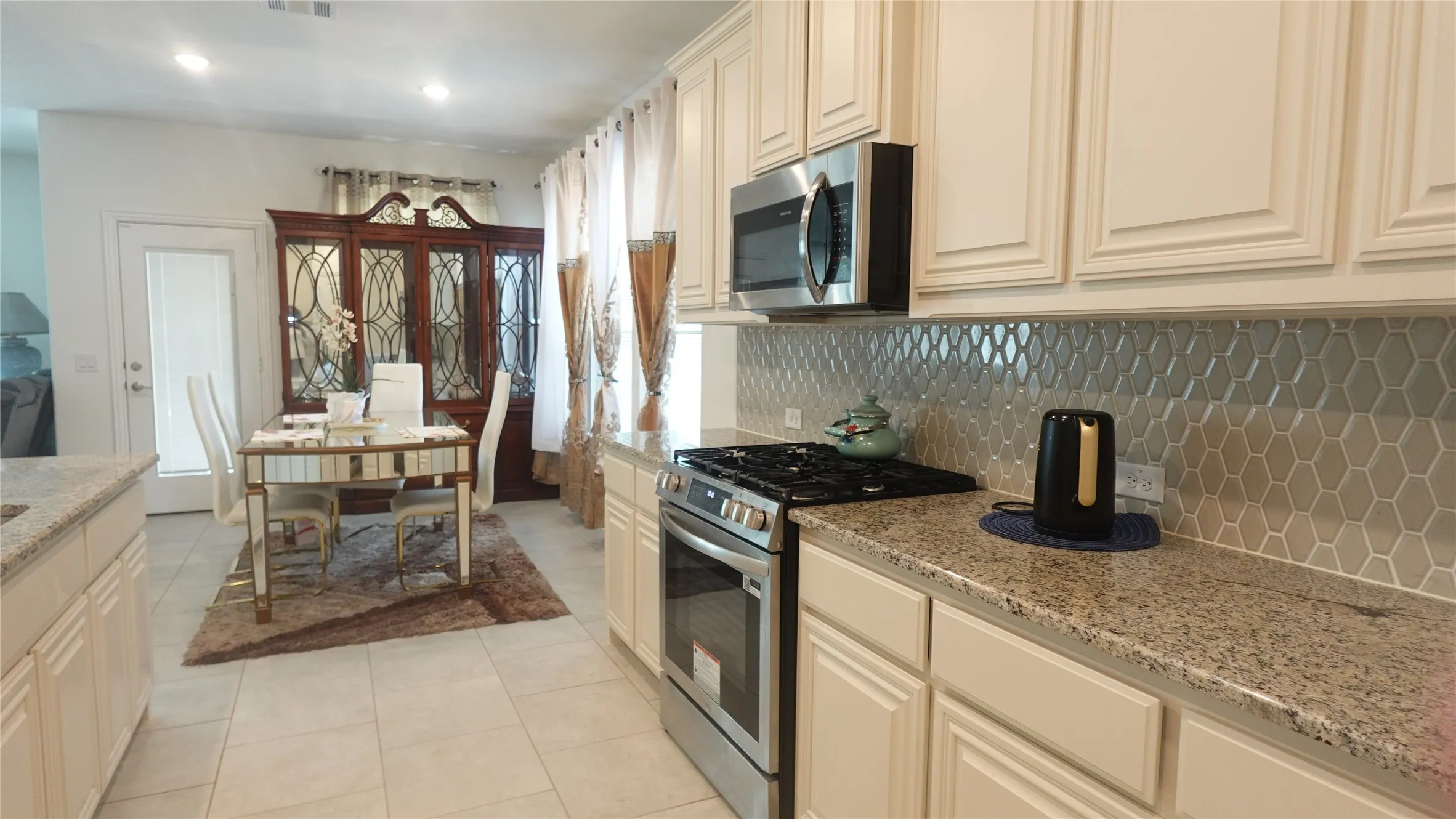 Kitchen featuring stainless steel appliances, upper and lower cabinetry, stone countertops, and a decorative tile backsplash