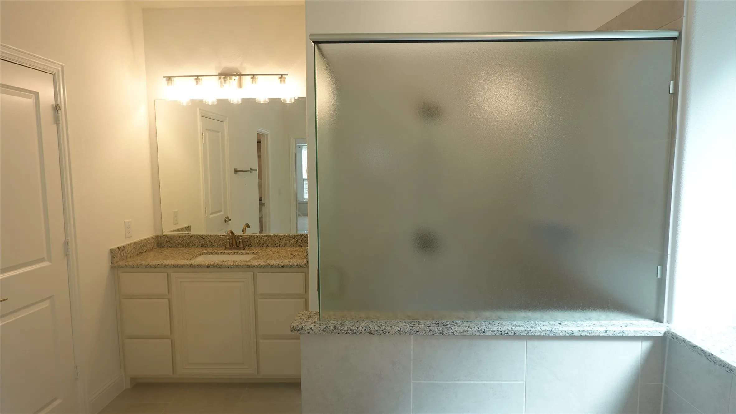 Vanity with stone-finish countertop, single basin sink, and ample cabinetry