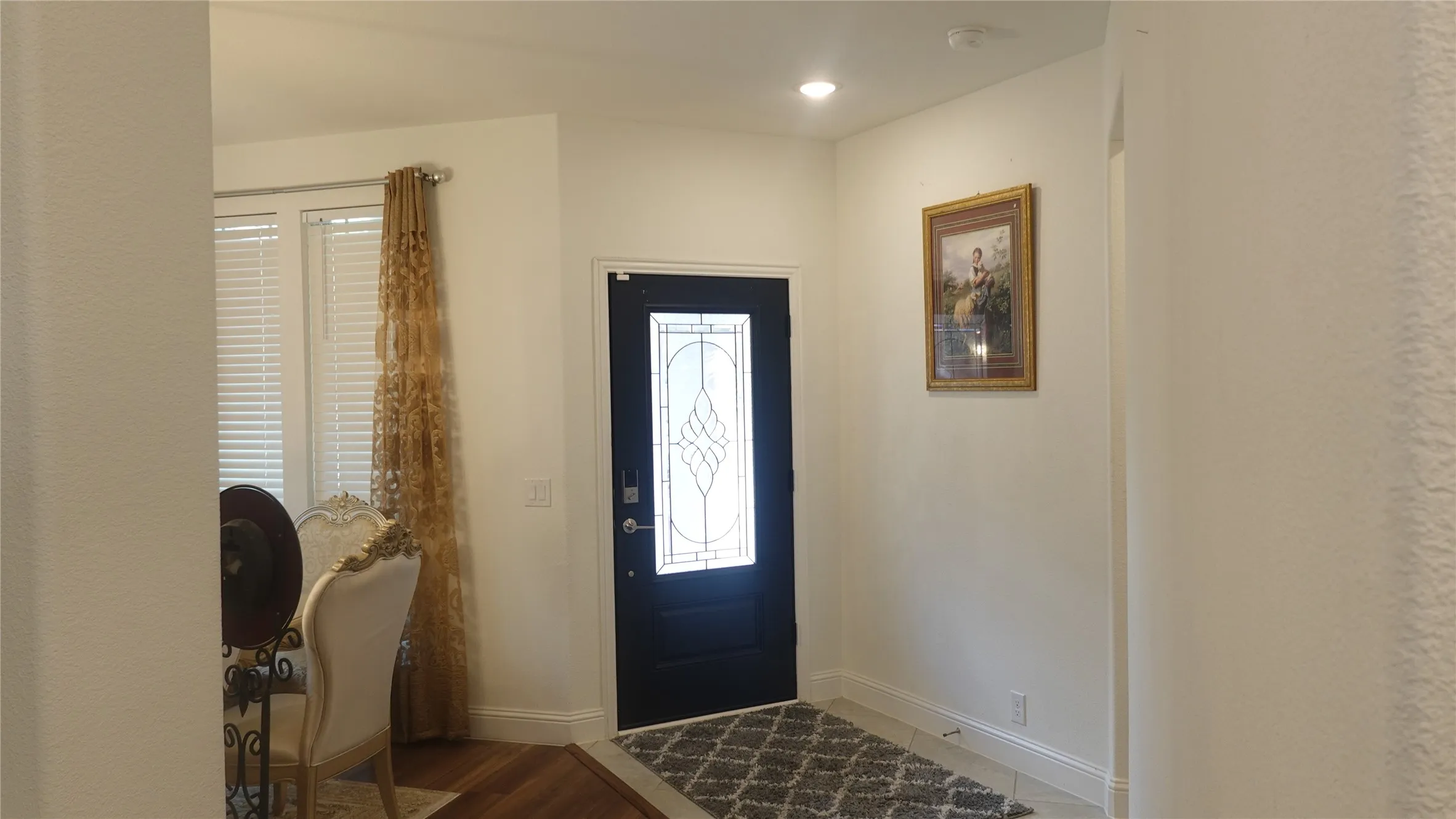 Entryway featuring a dark-paneled door with decorative glass, recessed lighting, and wood-finish flooring