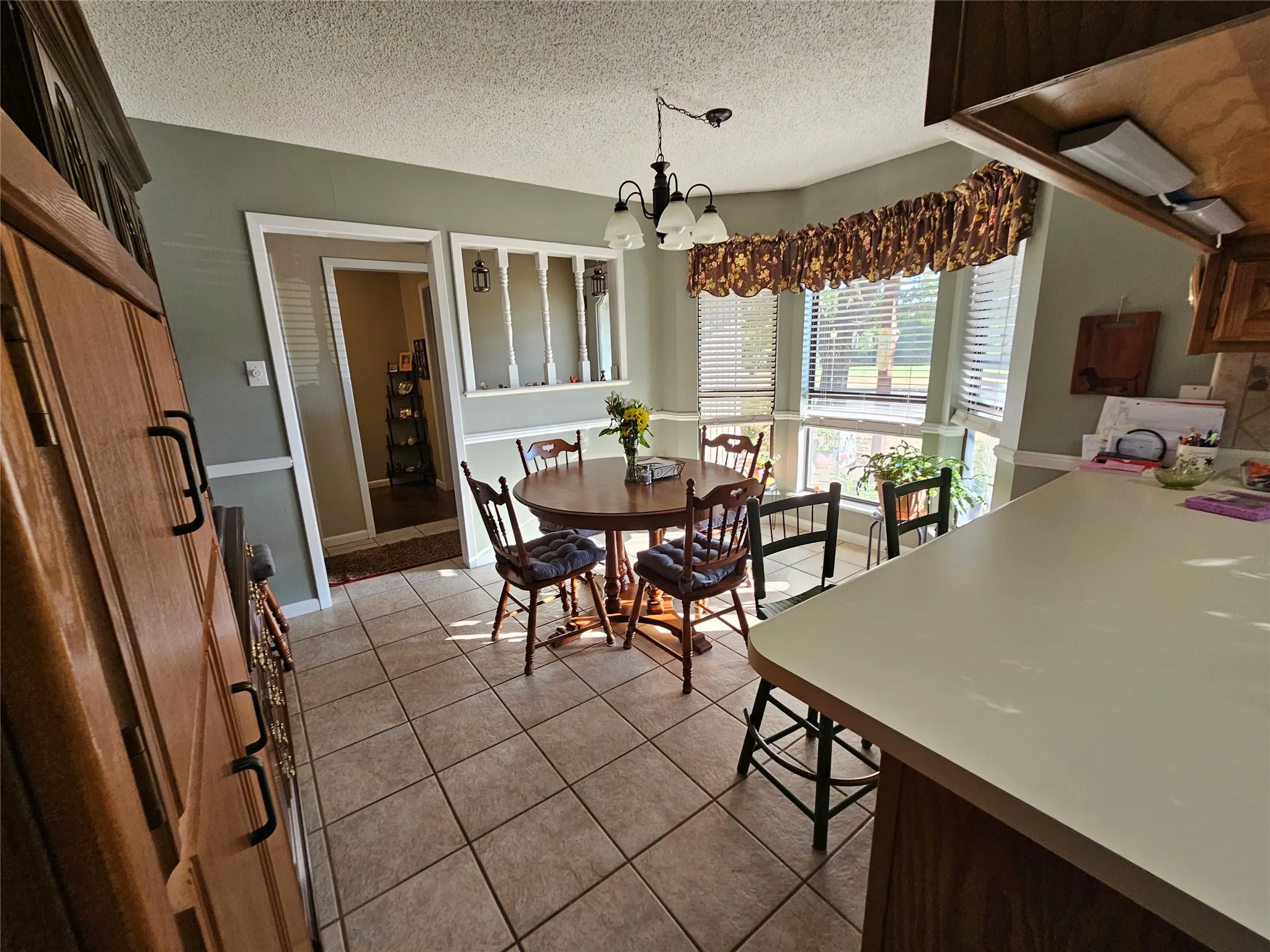 Bay window with blinds, tile flooring, built-in cabinetry, and a peninsula countertop