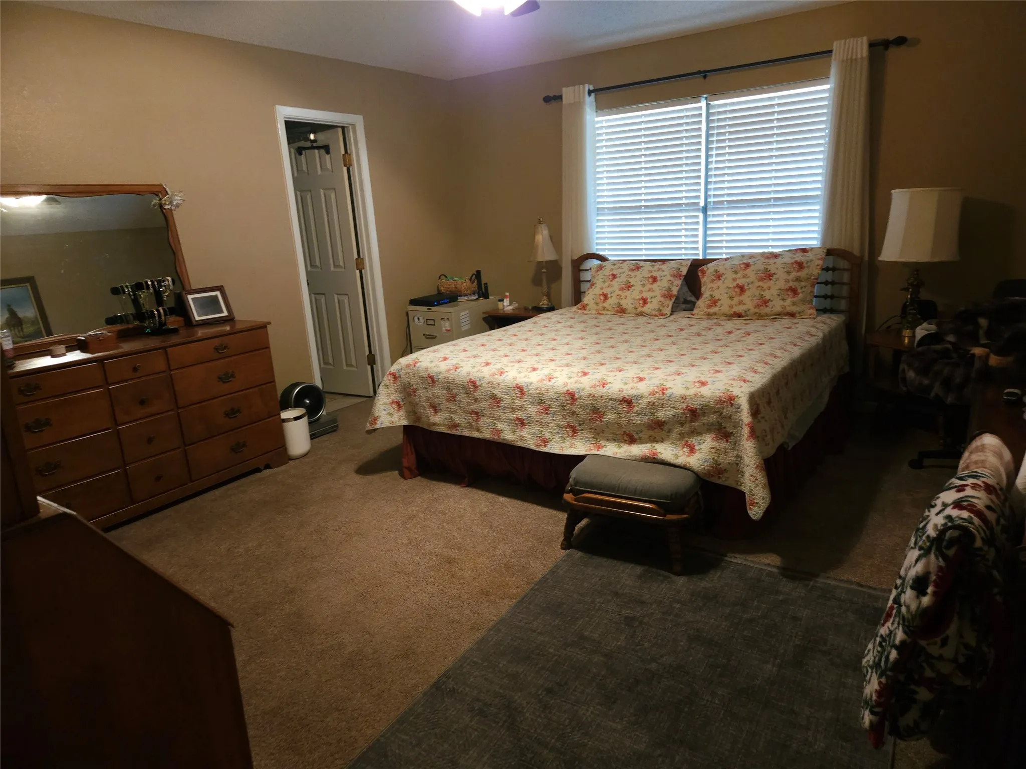 Primary bedroom featuring window with horizontal blinds and drapery rods