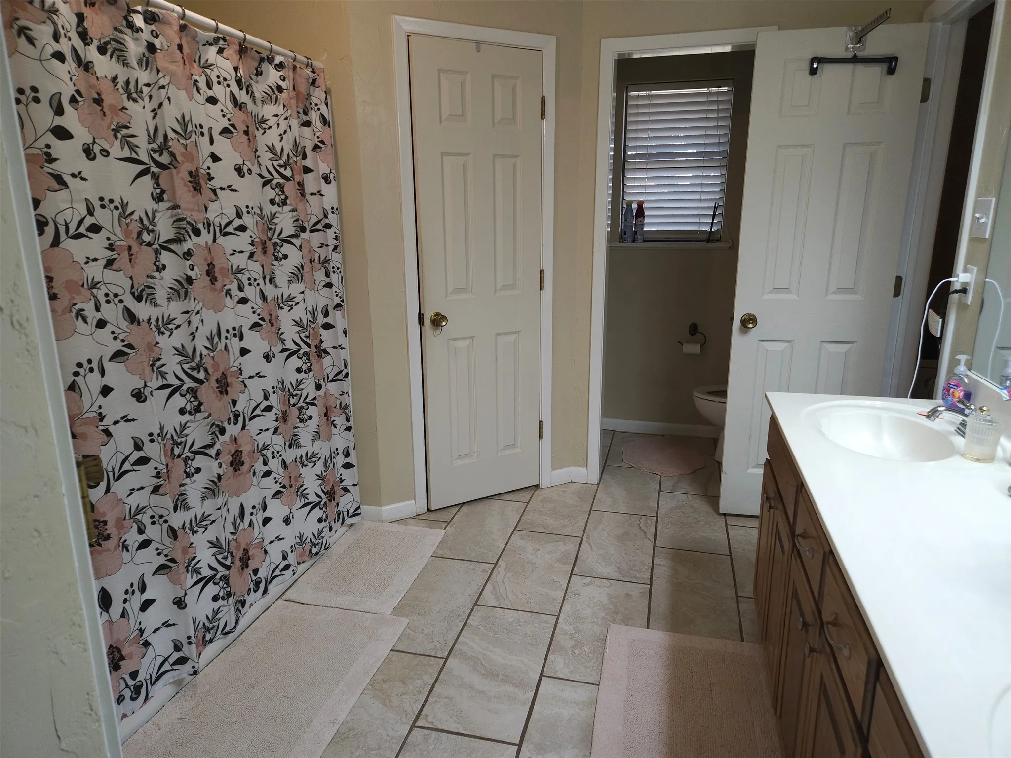 Tile flooring, vanity with integrated sink, wood-finish cabinetry and toilet area