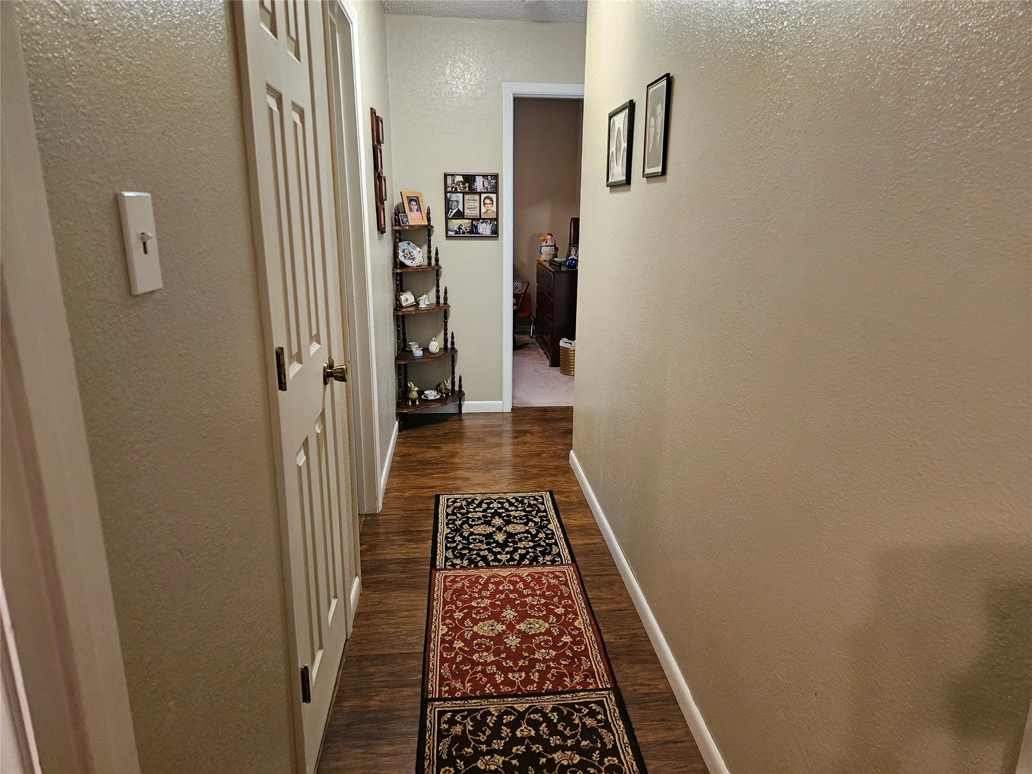 Wood-finish flooring throughout the hallway, featuring light-toned walls and classic paneled doors