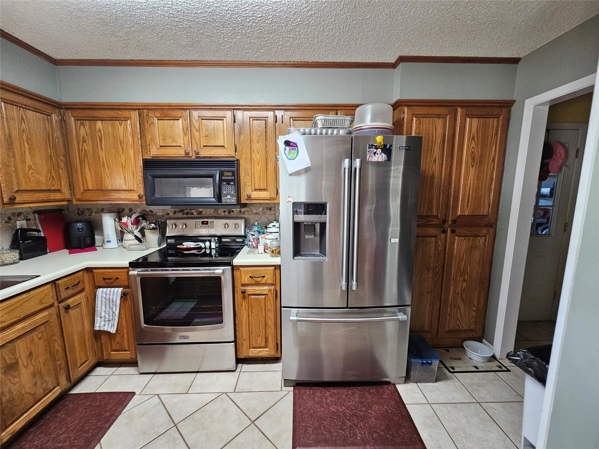 Kitchen featuring wood cabinetry, stainless steel appliances, tile flooring, and a built-in pantry