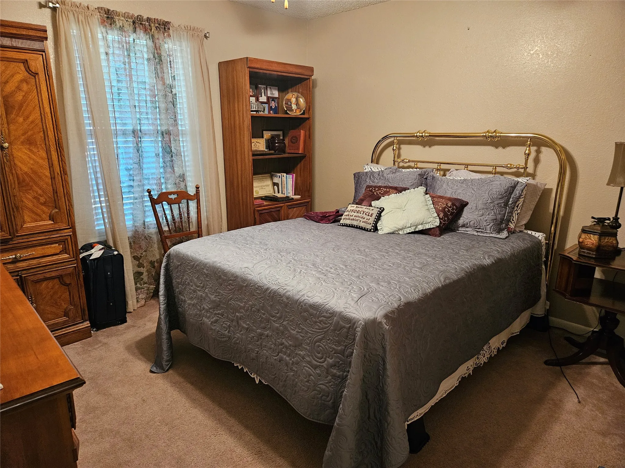 Carpeted bedroom with a window featuring blinds and sheer drapery