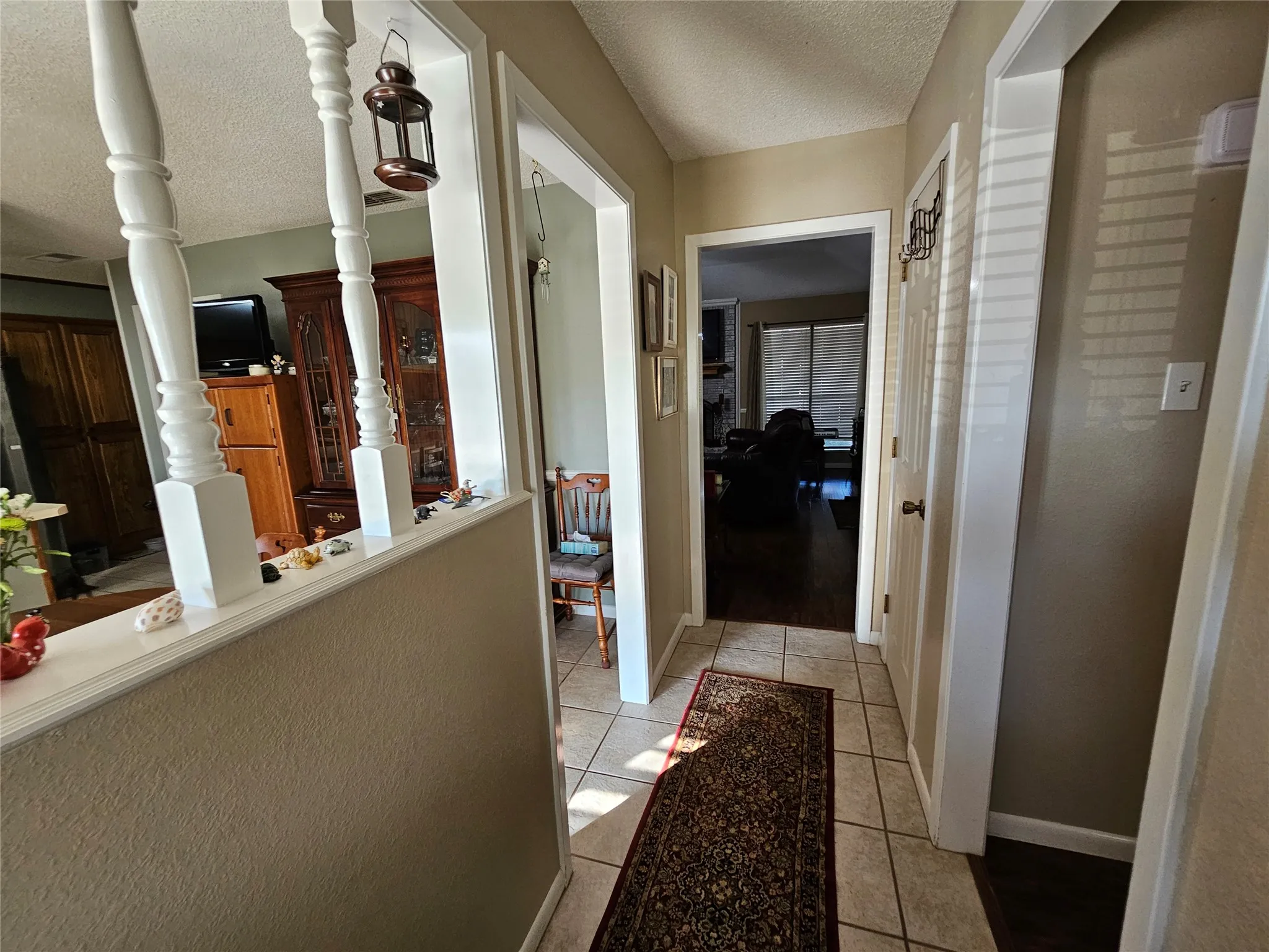 Hallway with ceramic tile flooring, textured walls, and white trim