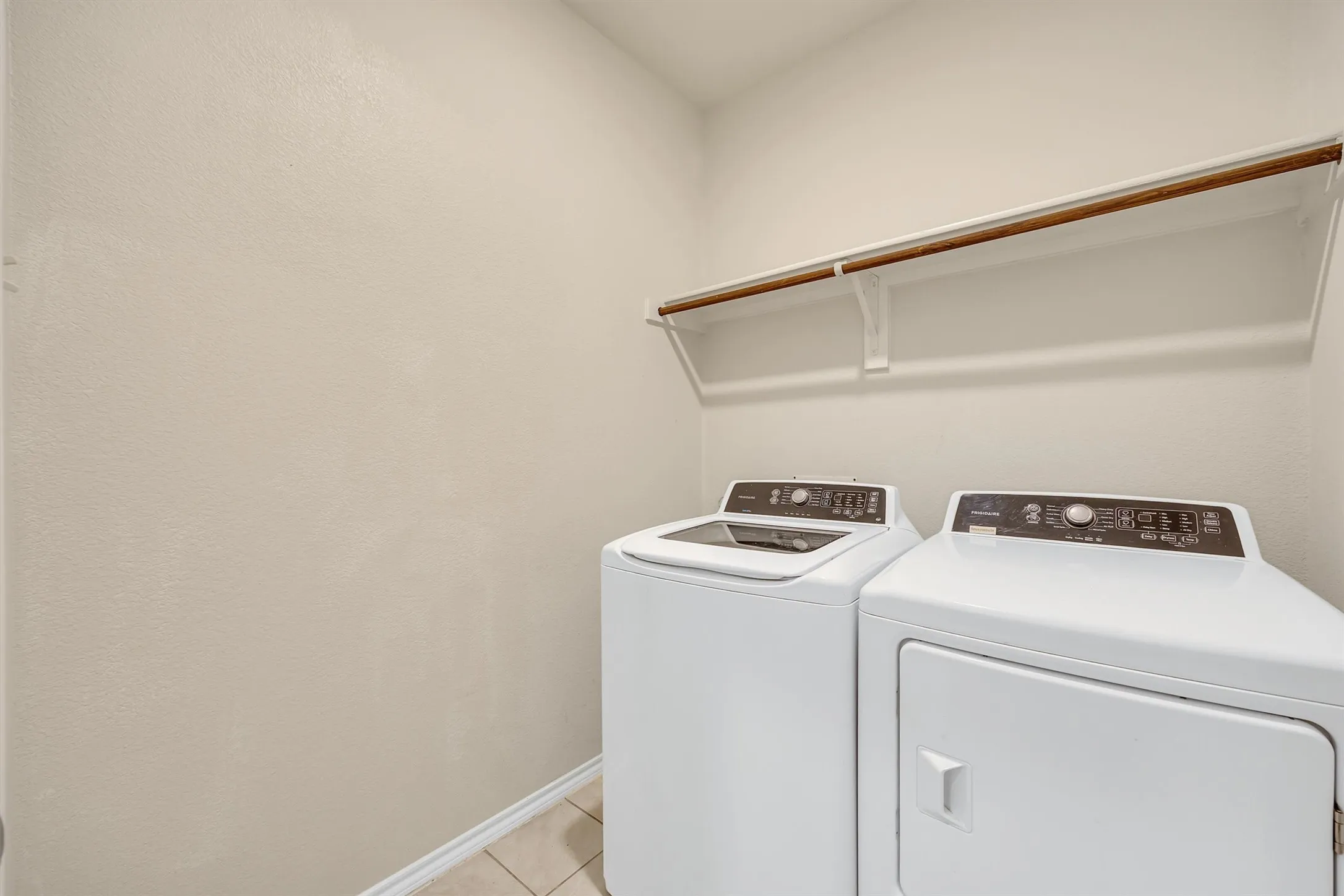 Laundry area featuring neutral wall tones, tile flooring, and a built-in hanging rod