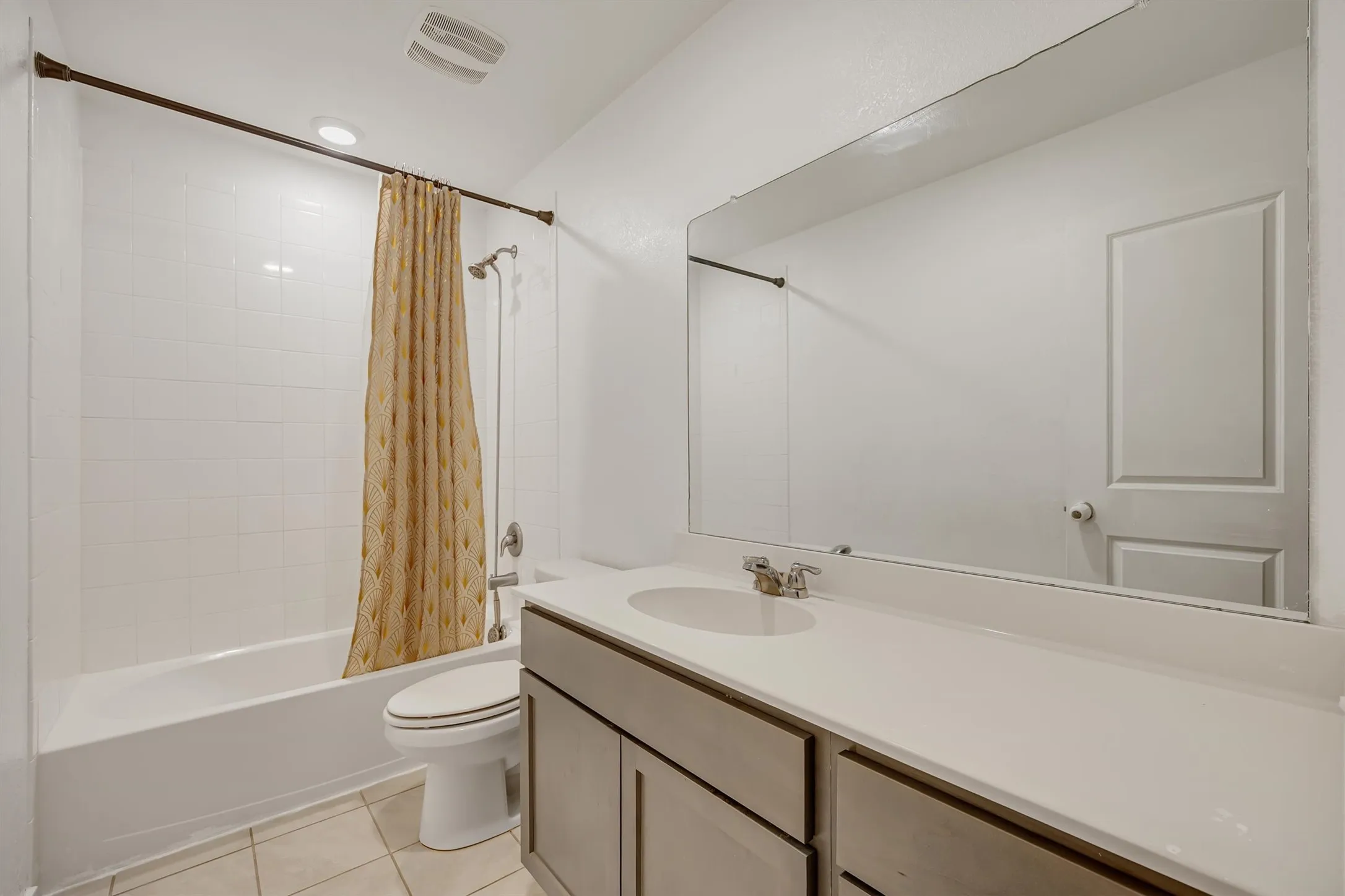 Full bathroom with a white tile shower-over-tub, extended vanity with an integrated sink, and a large wall-mounted mirror