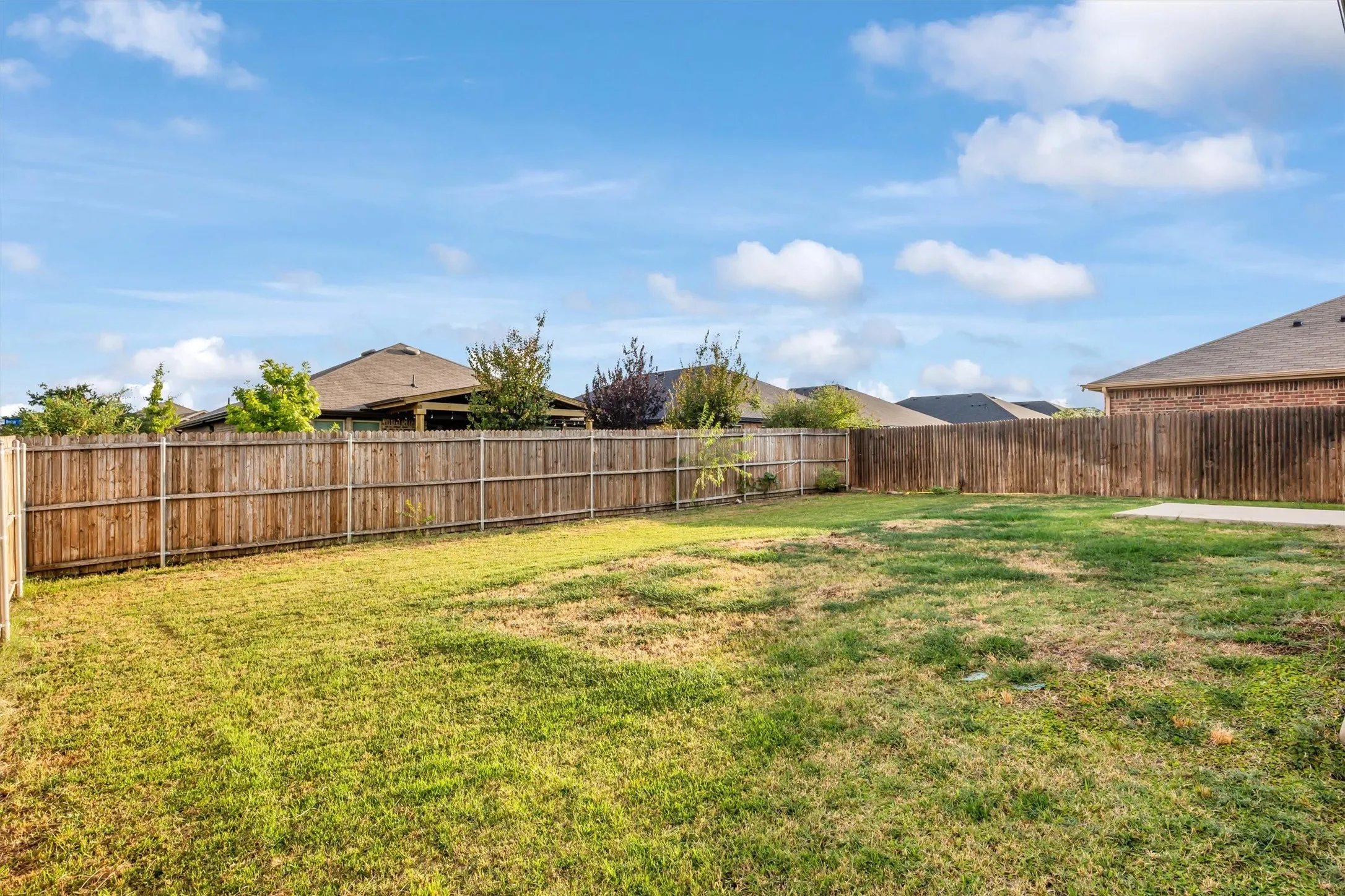 Spacious backyard area featuring a wood privacy fence and concrete patio