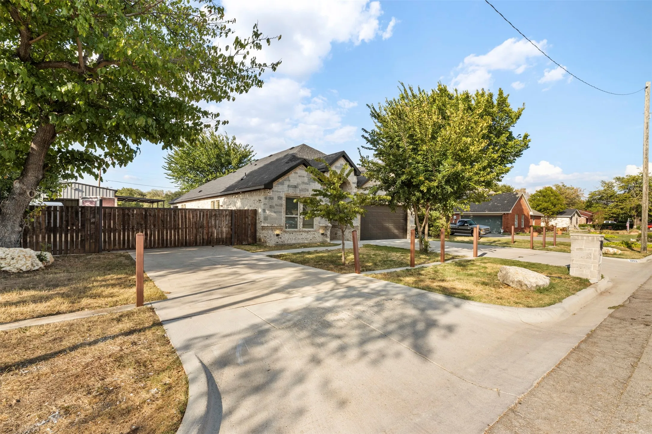 Stone veneer exterior, dark shingle roof, attached garage, concrete driveway, wood privacy fence