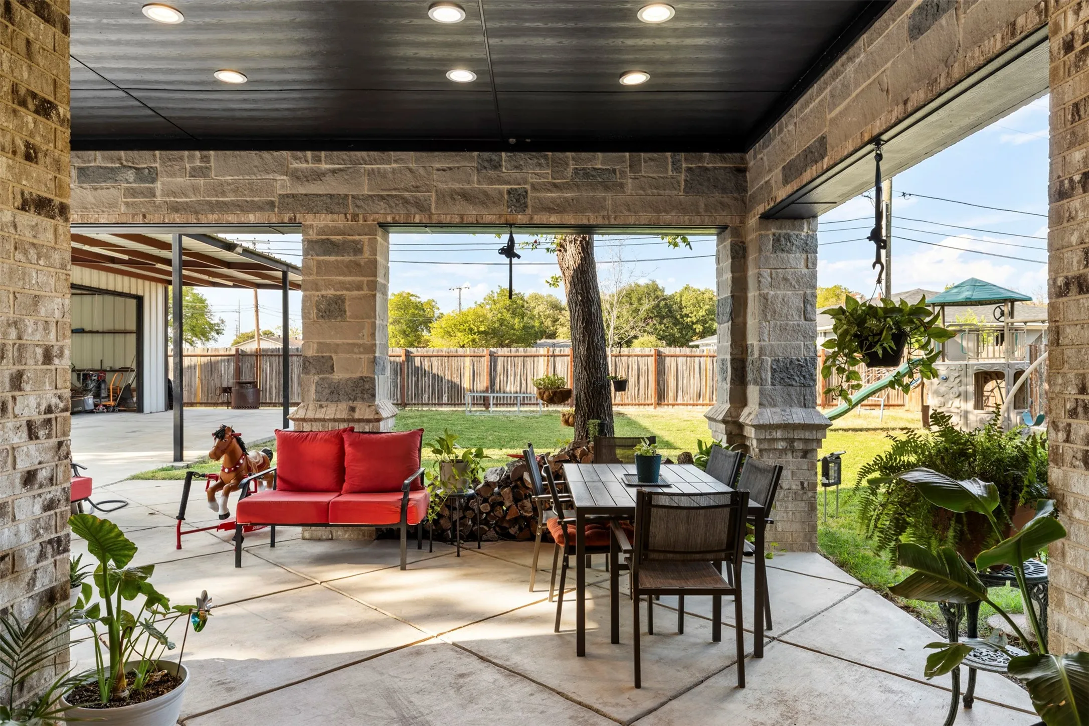 Covered patio with recessed lighting, stone columns, and a concrete slab
