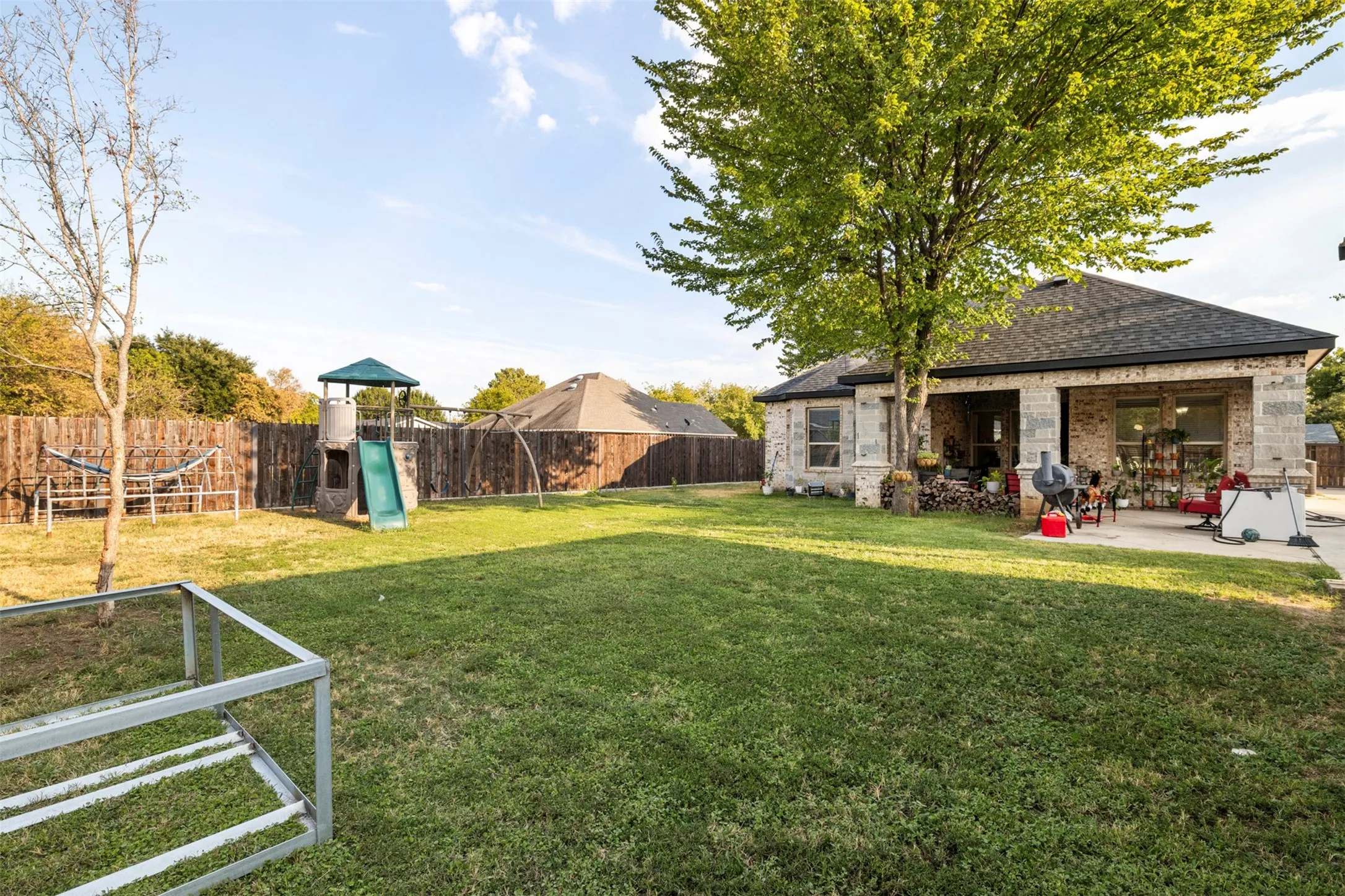 Expansive backyard featuring a manicured lawn, established trees, and a wooden privacy fence