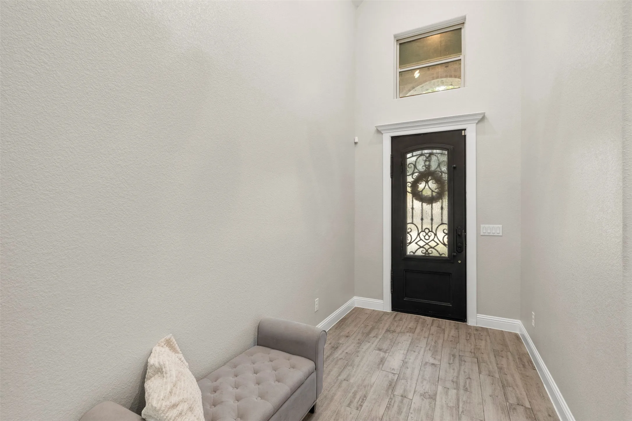 Arched transom window, wood-finish flooring, decorative glass door, and a high ceiling