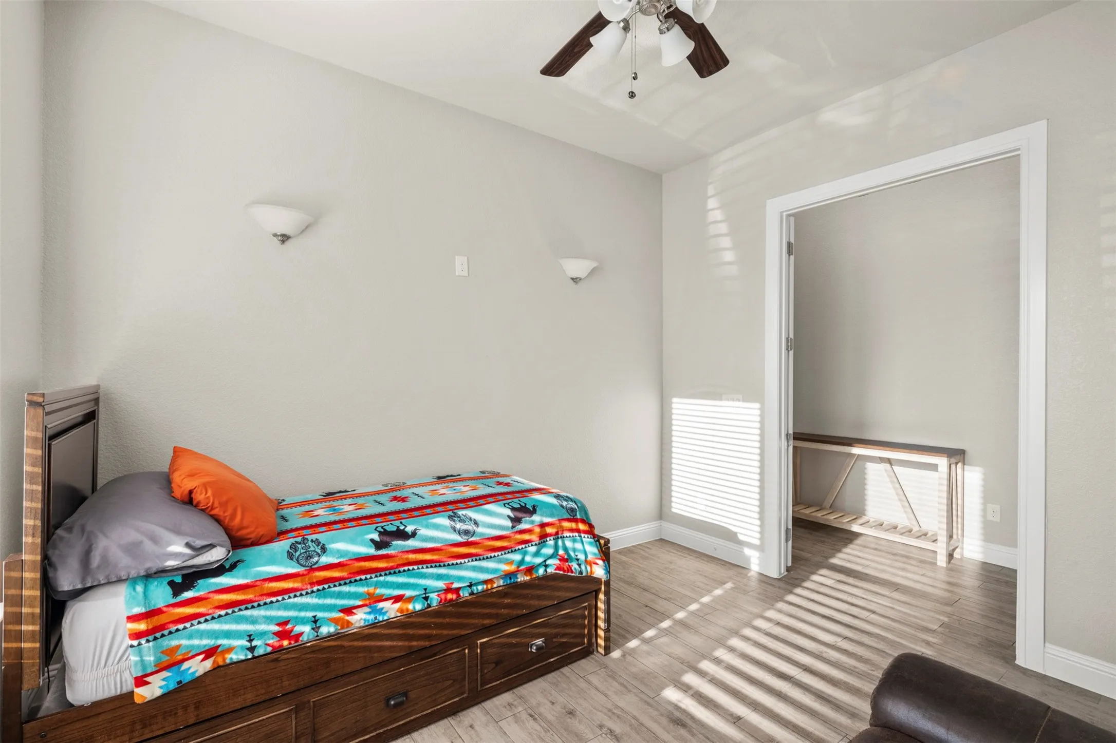Neutral-toned walls, wood-finish flooring, and a ceiling fan with light fixture