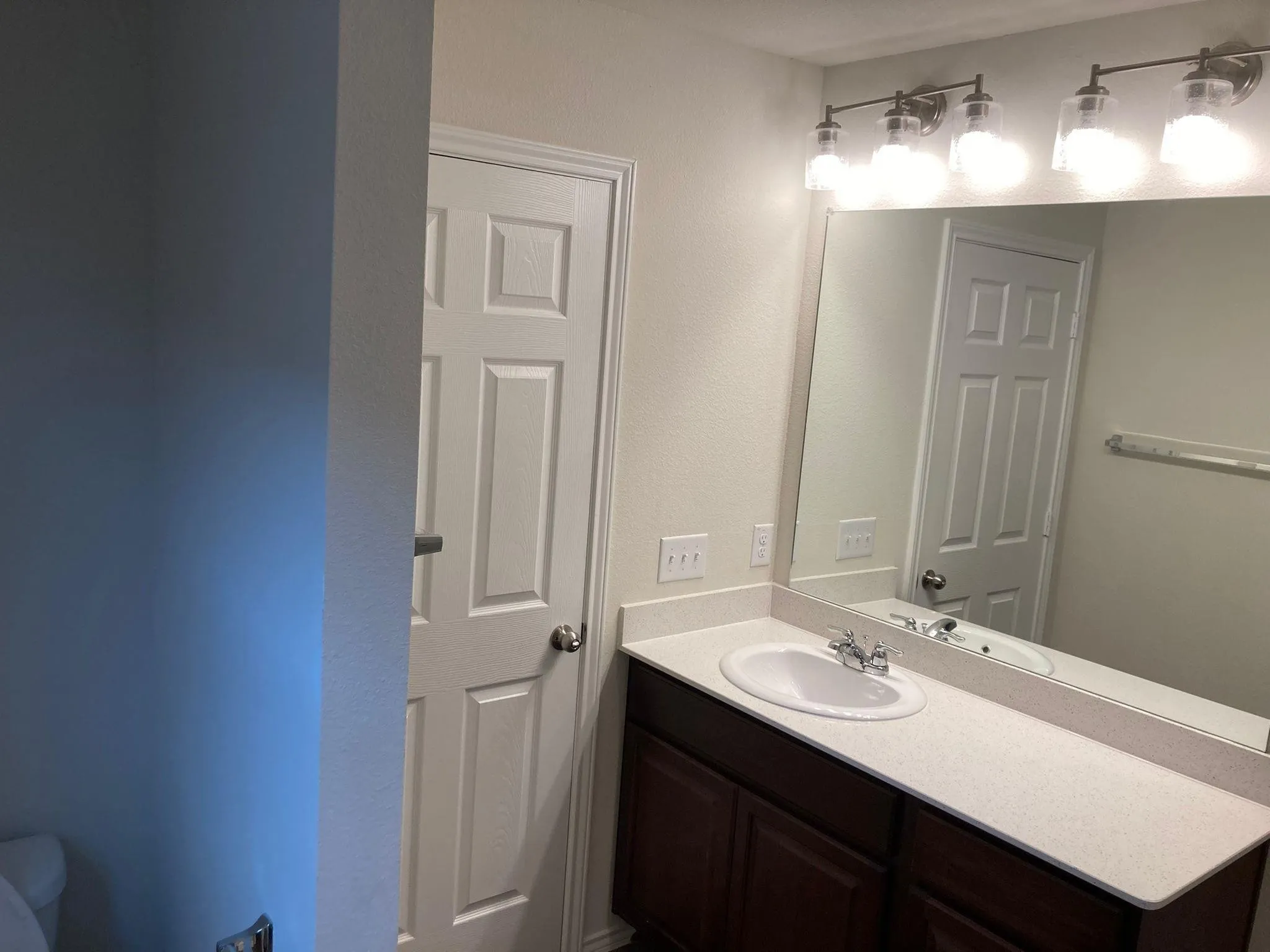 Vanity with a single sink, light-colored countertop, and dark wood-finish cabinetry