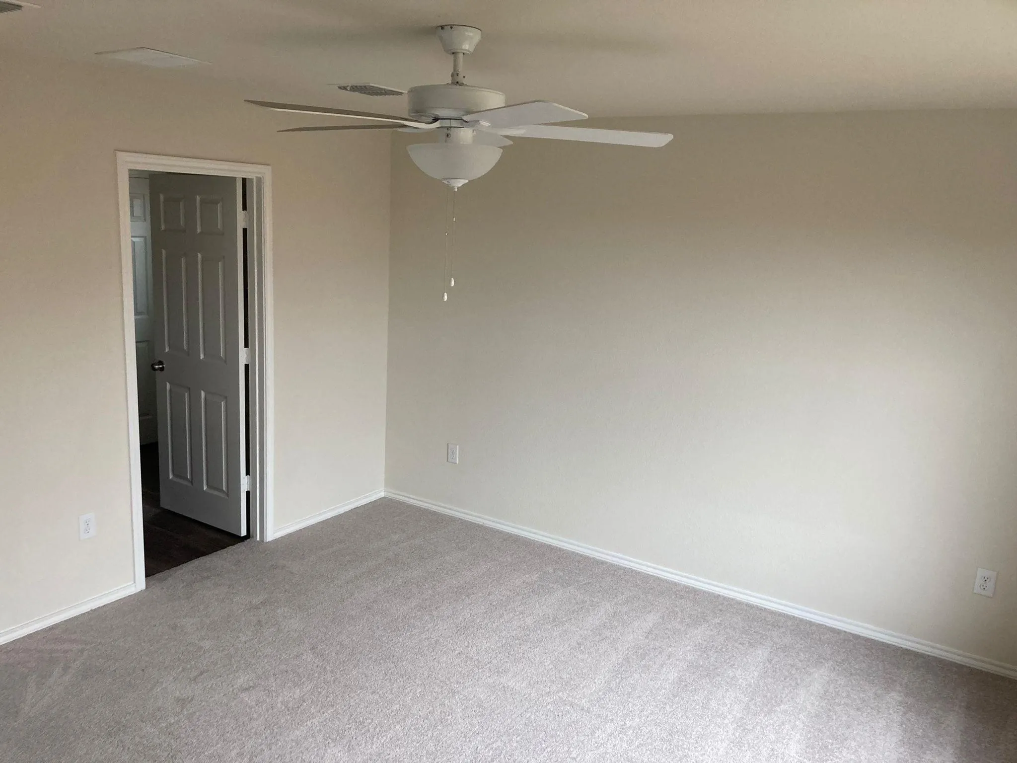 Neutral tone walls with soft carpet flooring and a ceiling fan