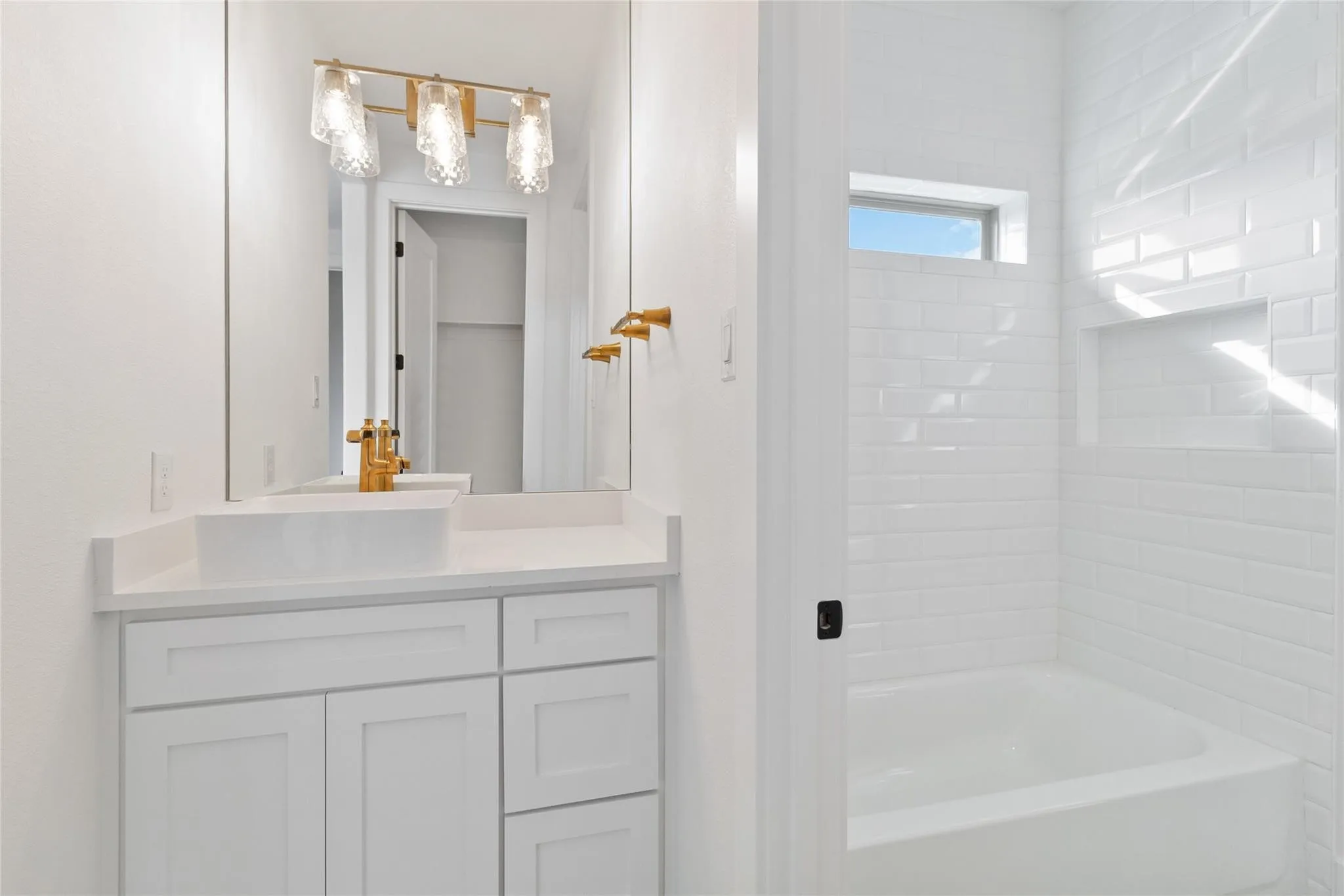 White shaker-style vanity with a vessel sink, gold-toned faucet, and rectangular mirror