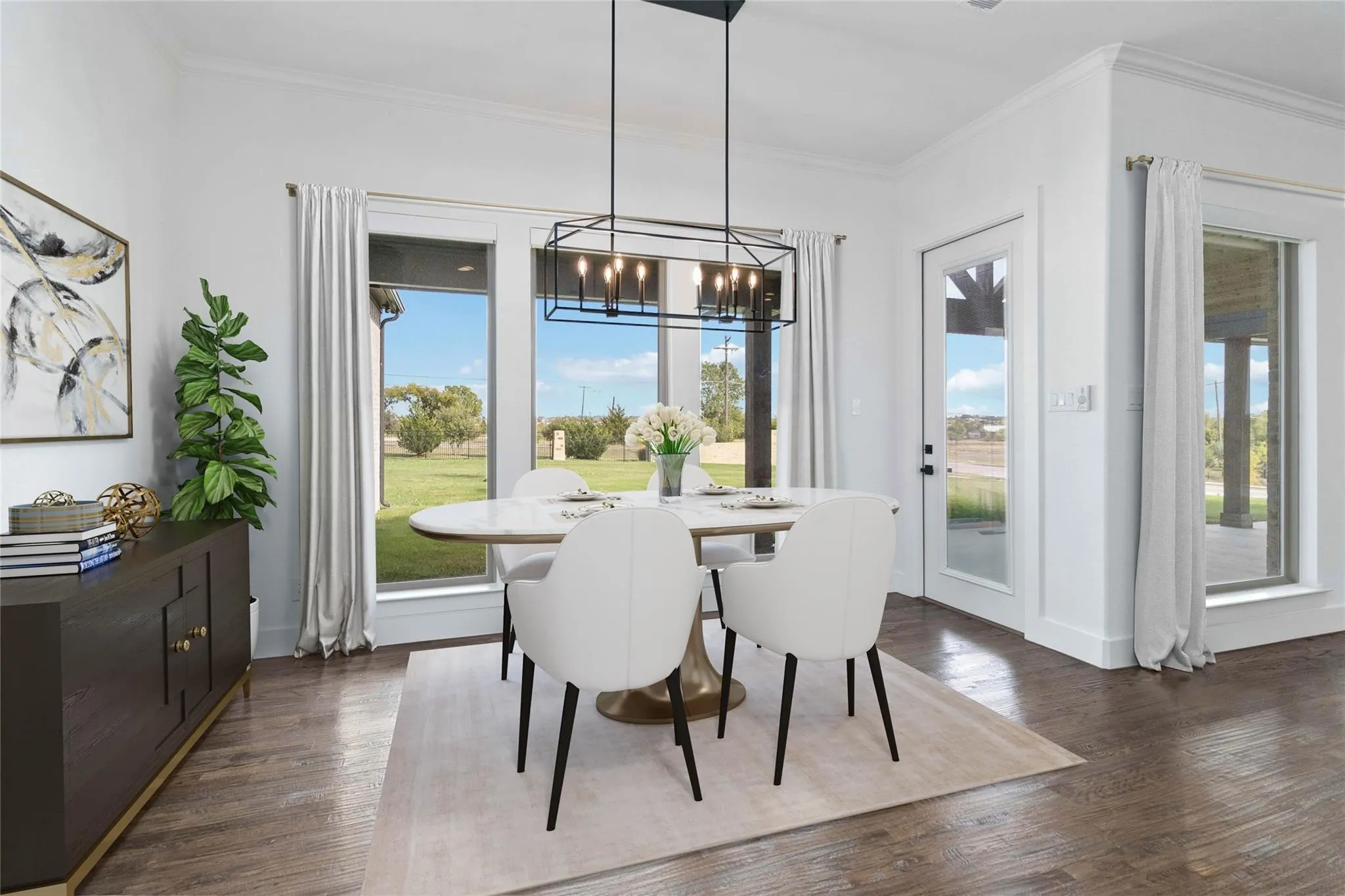 Spacious dining area featuring wood-finish flooring, a contemporary linear chandelier, and expansive windows