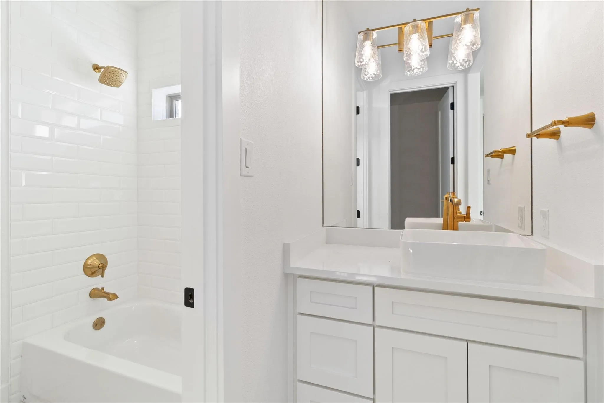 White subway tile shower surround with gold-finish fixtures