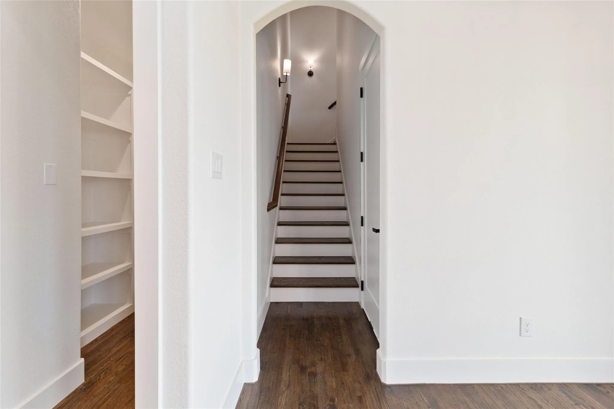 Archway entry to a staircase with wood treads and white risers